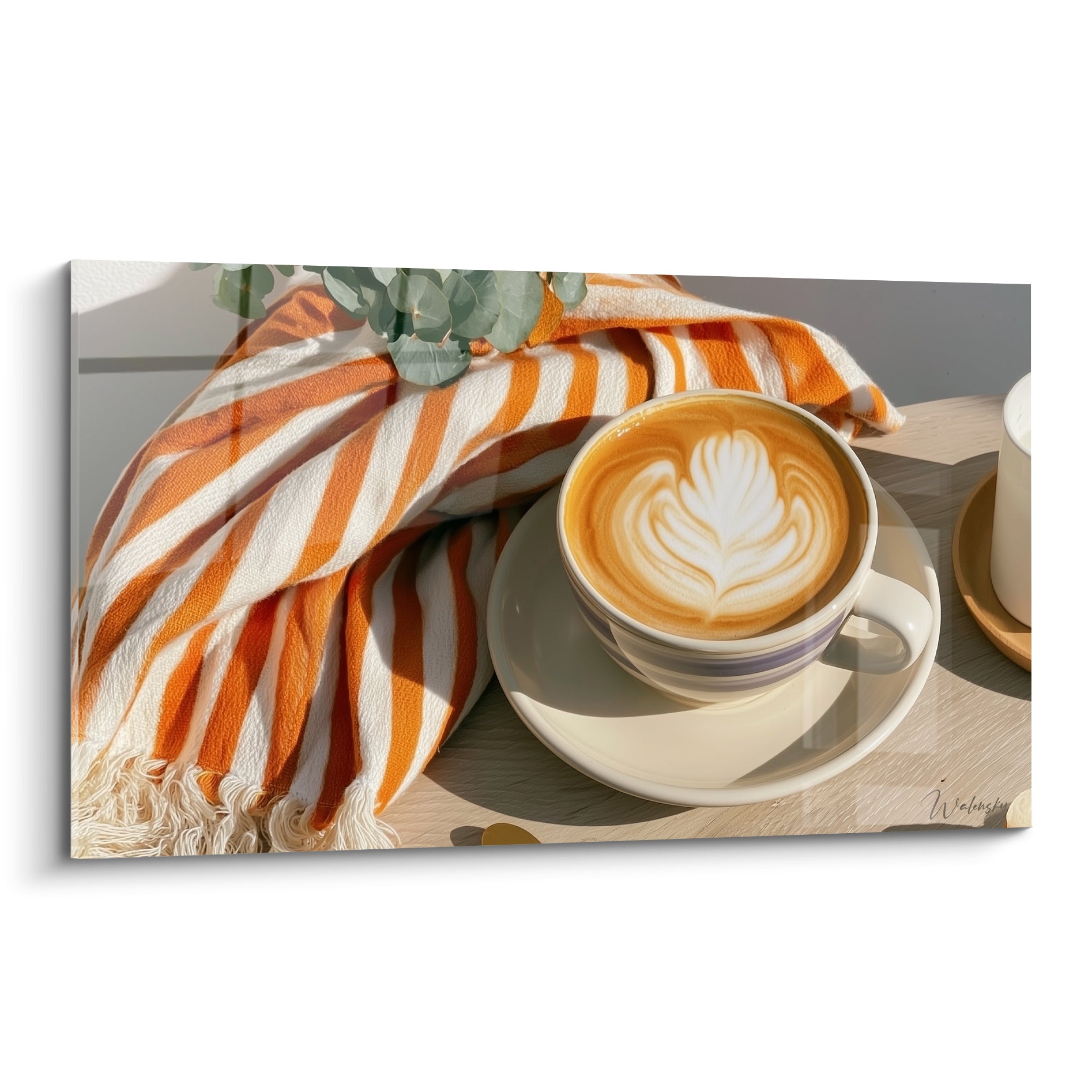 Cappuccino orange et blanc au latte art, tasse posée sur plaid rayé texturé