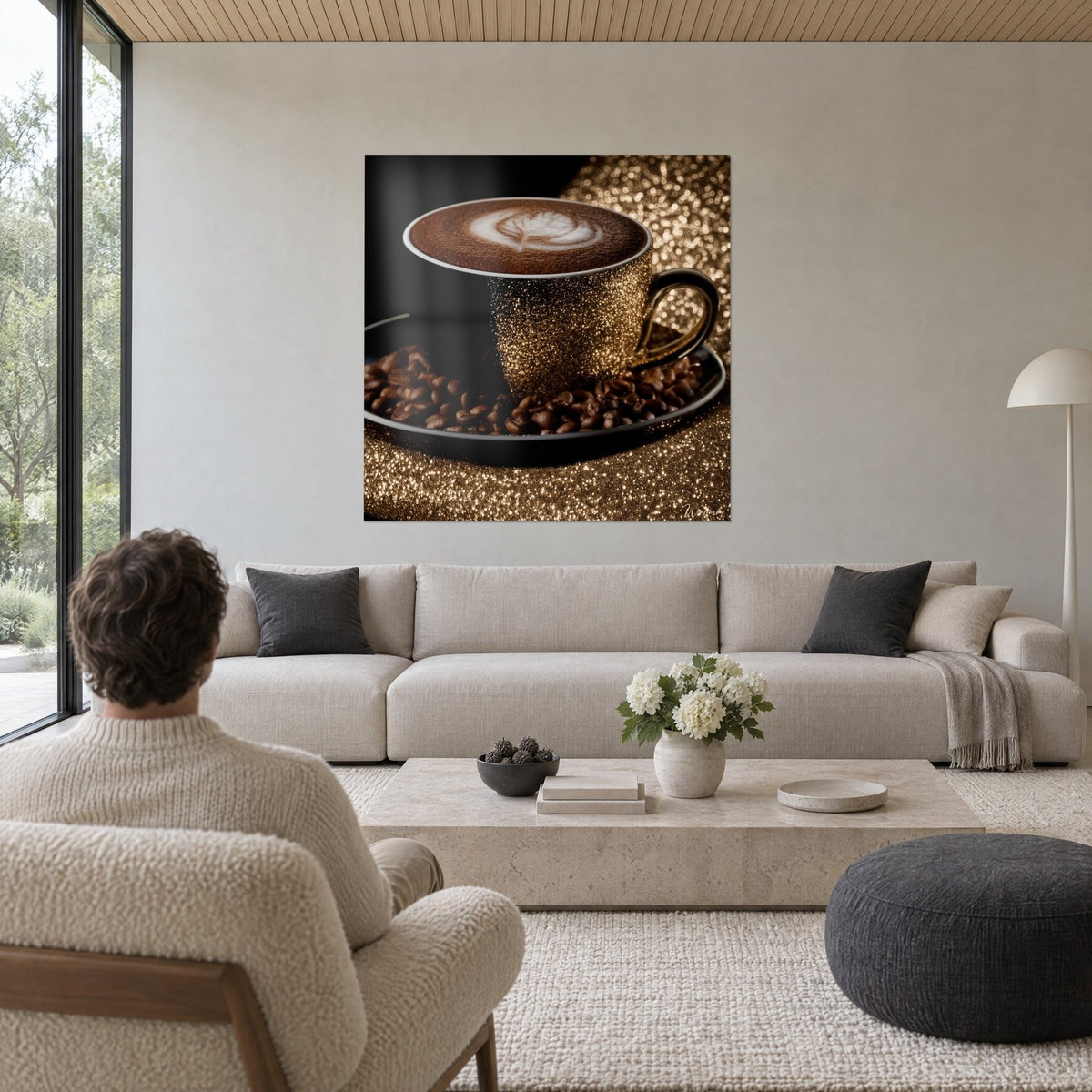 Quadro tazza nera con glitter dorato e schiuma di cappuccino su chicchi tostati, uomo di spalle, sopra un divano in un soggiorno luminoso