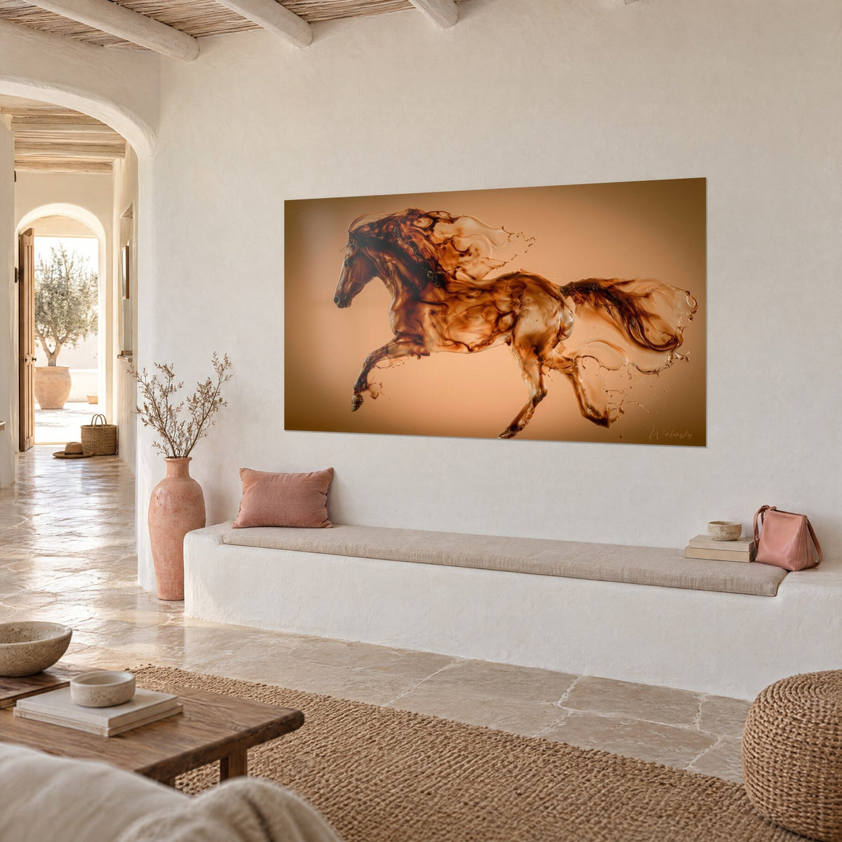 Quadro di uno stallone liquido ramato con schizzi traslucidi su sfondo albicocca, muro intonacato bianco e panca in pietra chiara