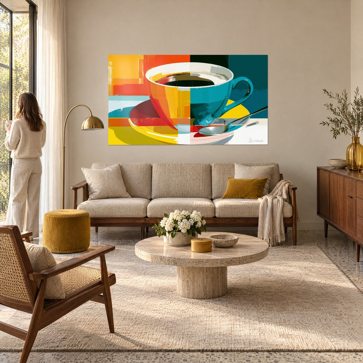 Tableau tasse de café coupée en deux, moitié orange et jaune, moitié bleu canard, au-dessus d'un canapé dans un salon lumineux