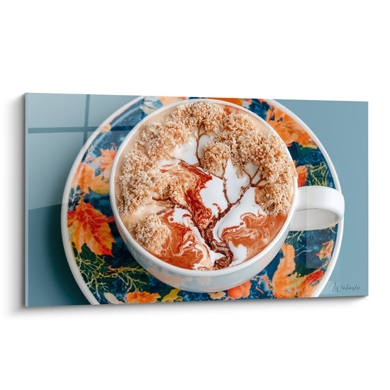 Tasse blanche à latte art doré sur soucoupe bleu marine et feuilles orange, tableau café