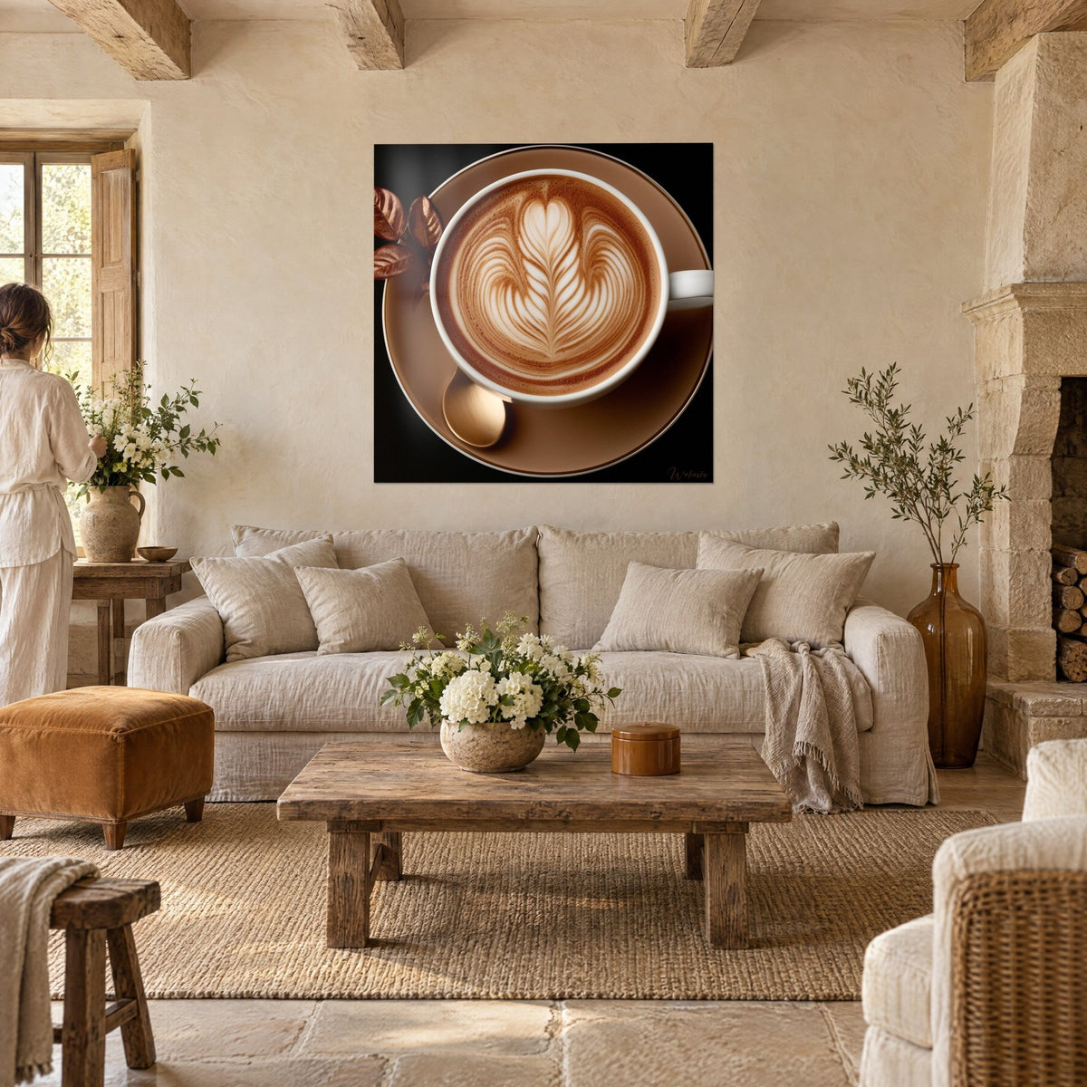 Quadro cappuccino con schiuma a forma di piuma color crema e caramello, piattino beige, due persone di schiena sopra un divano in un soggiorno luminoso