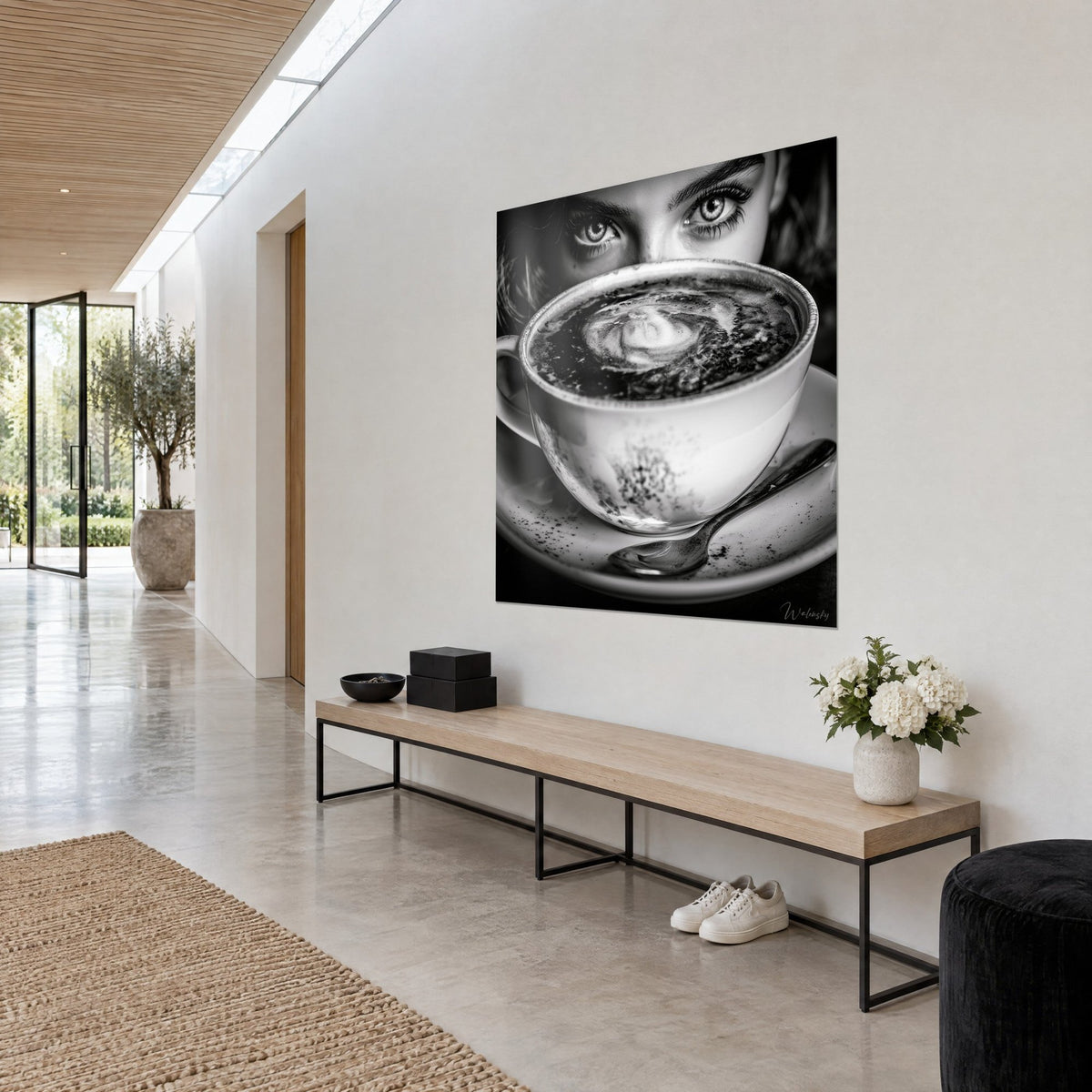 Tableau yeux clairs cernés de cils noirs derrière une large tasse blanche, mousse grise, mur crème, banc de bois en couloir