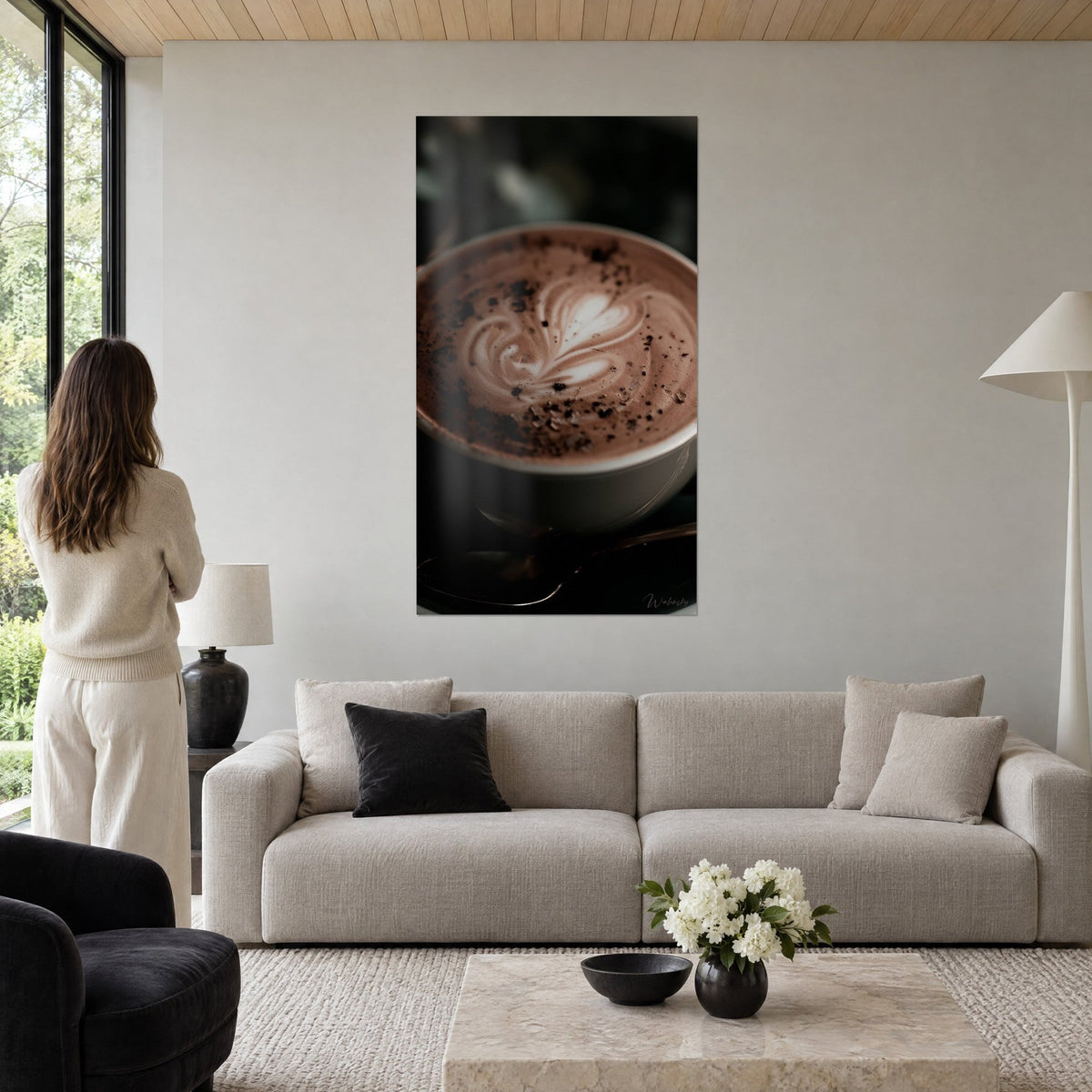 Tableau cappuccino au cœur de mousse crème, éclats de cacao sur fond brun, femme de dos, au-dessus d'un canapé dans un salon lumineux
