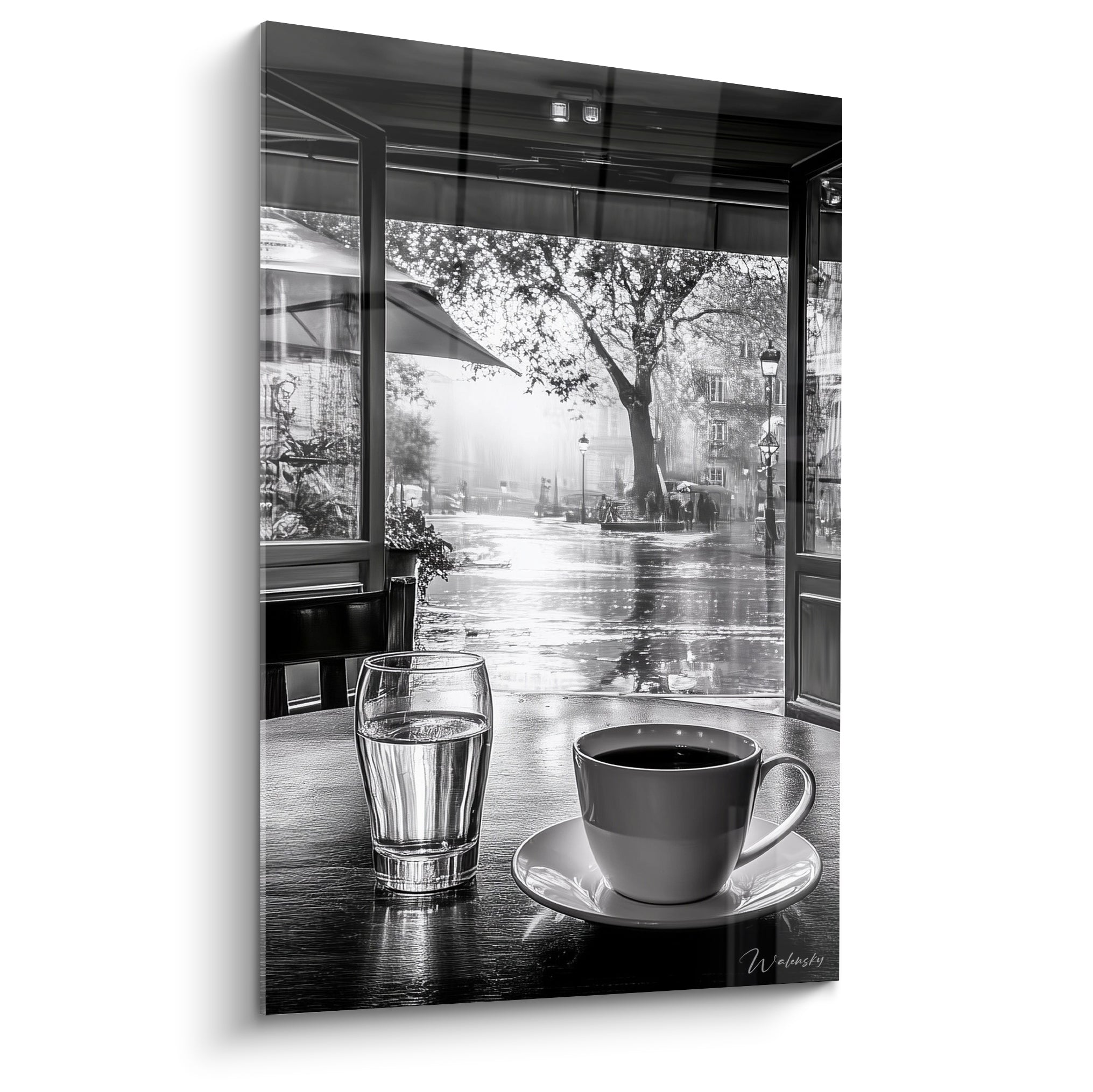 Tasse de café noire et verre d'eau sur table en bois face à une rue pluvieuse en noir et blanc