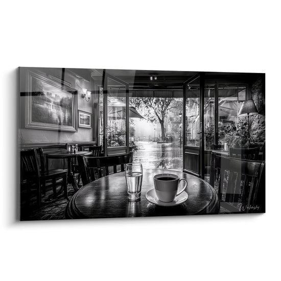 Café parisien en noir et blanc, tasse fumante sur table ronde face à une rue pluvieuse