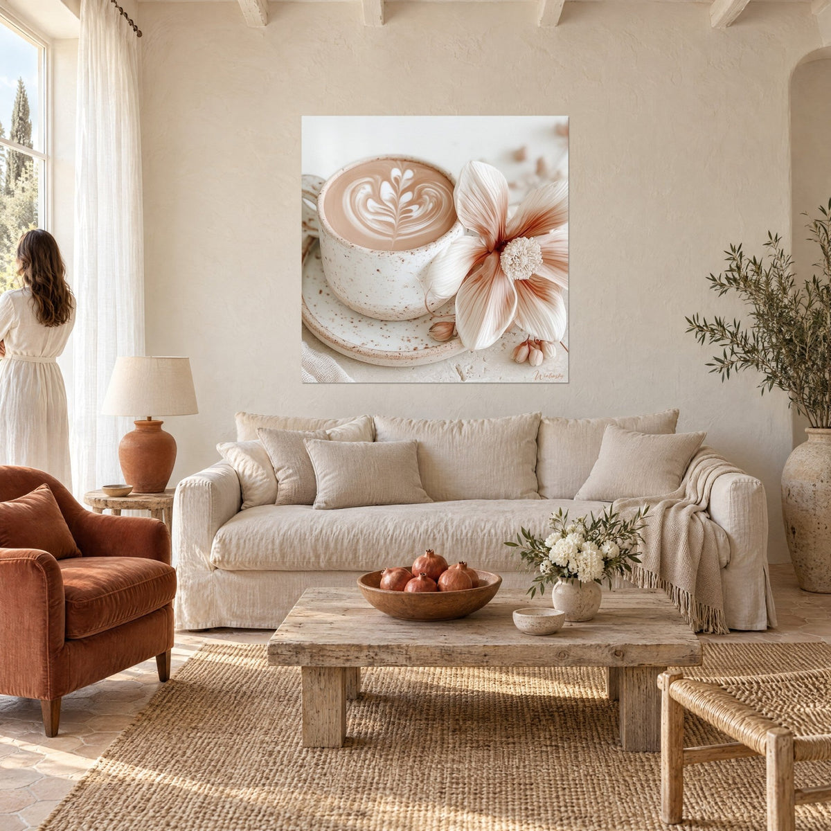 Tableau tasse de cappuccino à l'écume en feuille, fleur rose poudré, mur beige, au-dessus d'un canapé dans un salon lumineux