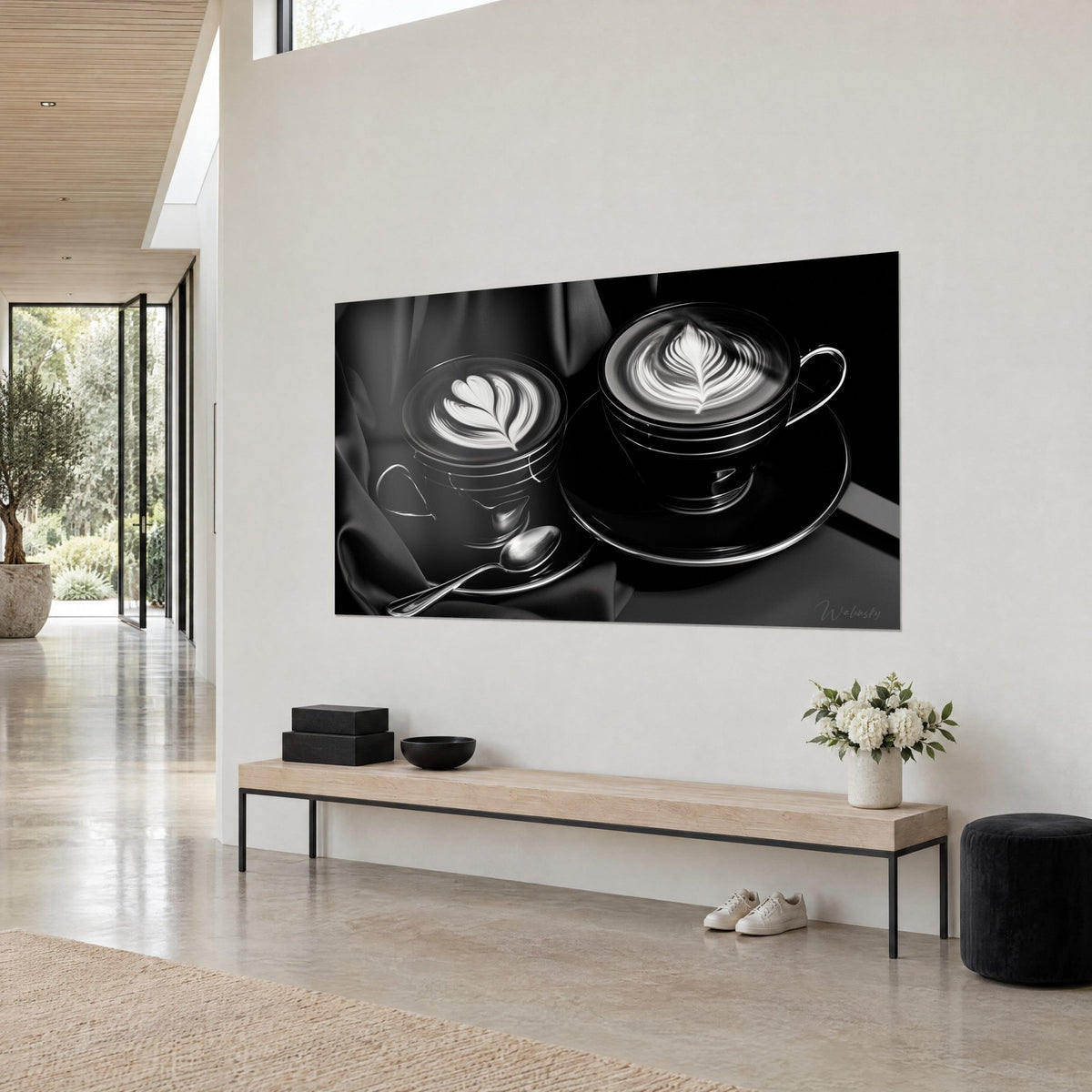 Quadro latte art a cuore e piuma, crema avorio su fondo nero, cucchiaino d'argento, parete bianca, vista di tre quarti, casa d'architetto