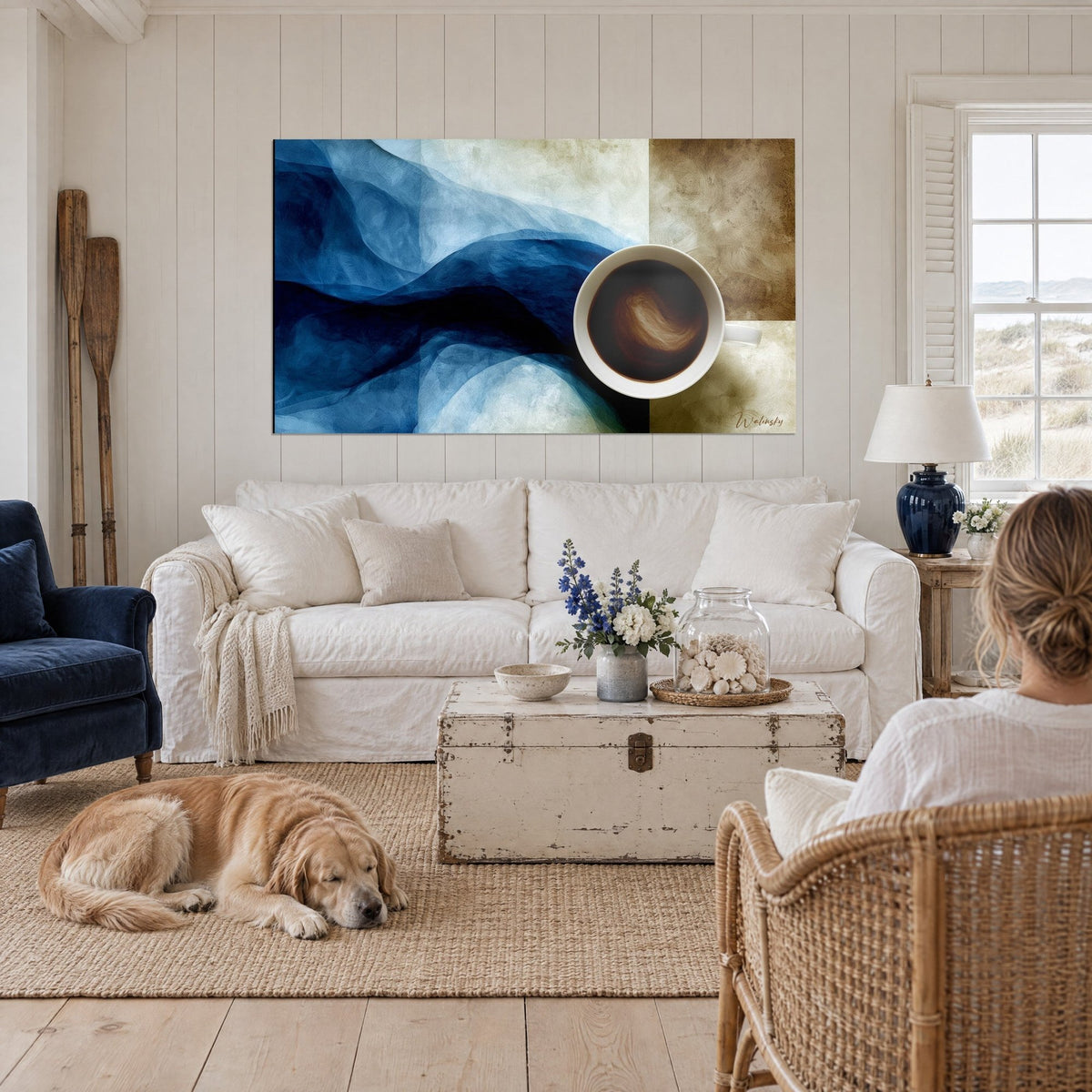 Quadro tazza di caffè vista dall'alto su onde di vela blu notte e ocra, sopra un divano in un soggiorno luminoso