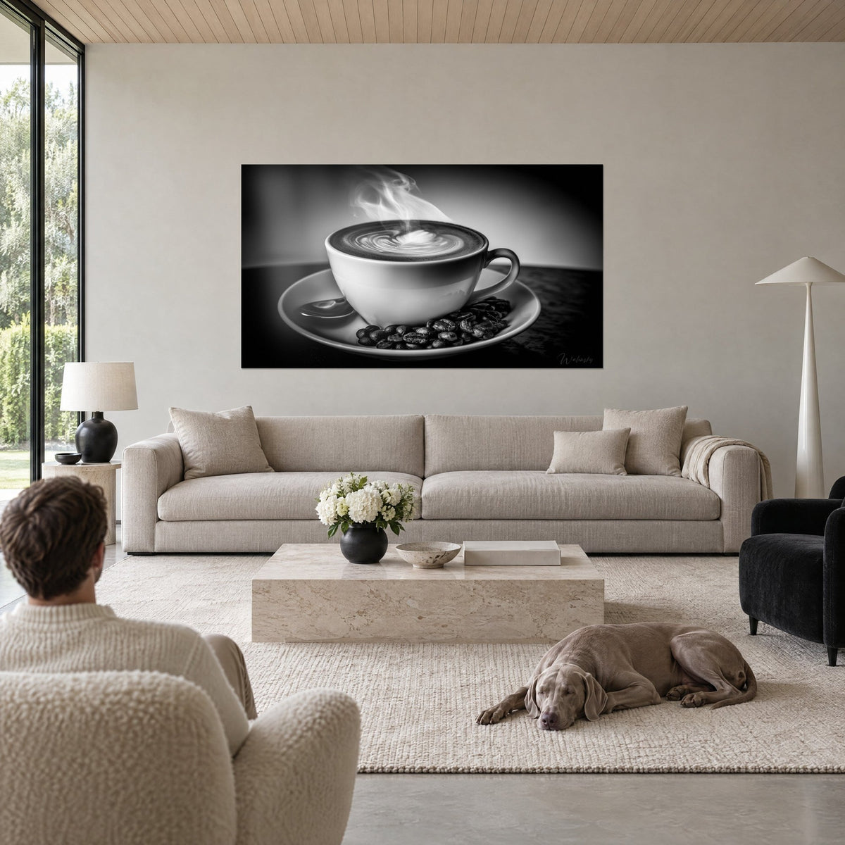 Quadro latte art a forma di cuore nel vapore, tazza bianca e chicchi neri, due persone di spalle sopra un divano in un soggiorno luminoso