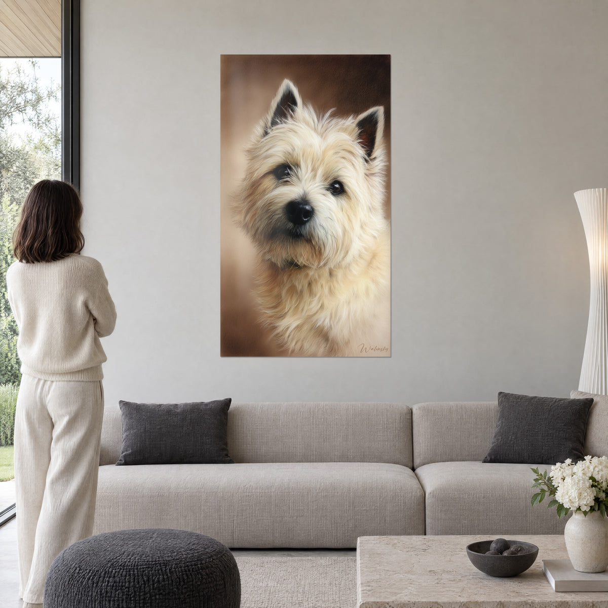 Πίνακας κρεμ cairn terrier με μαύρα αυτάκια, τρυφερό βλέμμα σε καφέ φόντο, γυναίκα από πίσω πάνω από έναν καναπέ σε φωτεινό σαλόνι