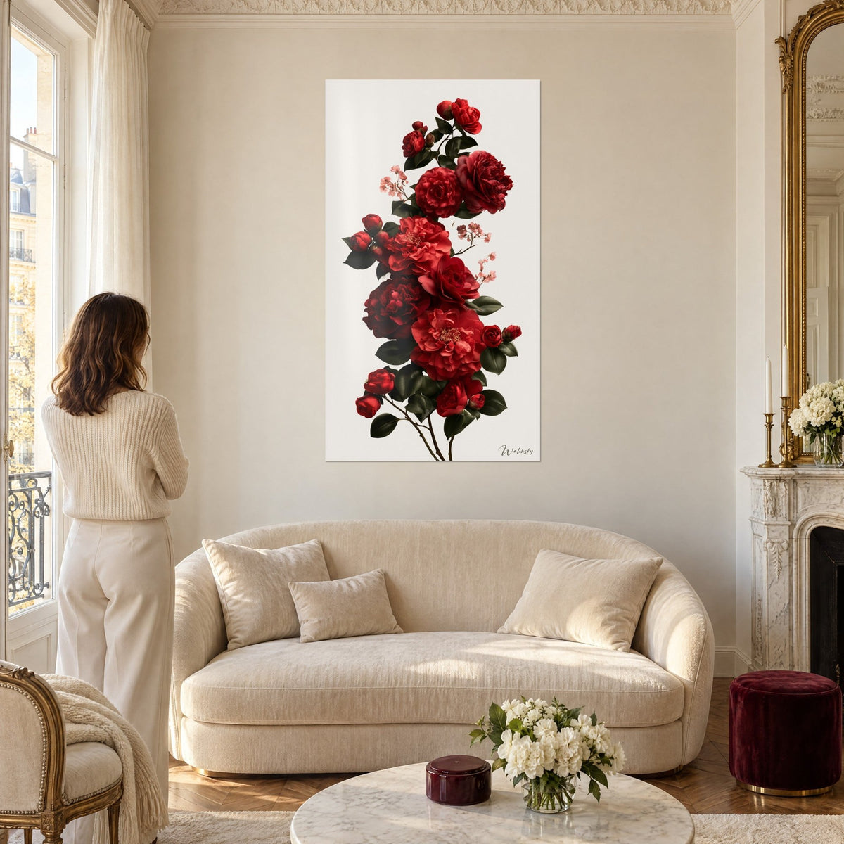 Cuadro con camelias rojas en cascada, peonías carmesí y follaje verde oscuro, mujer de espaldas, sobre un sofá en un salón luminoso