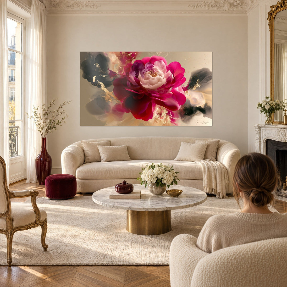 Wall art rosy purple camellia with gold accents and charcoal grey clouds, a woman seen from behind above a sofa in a bright living room