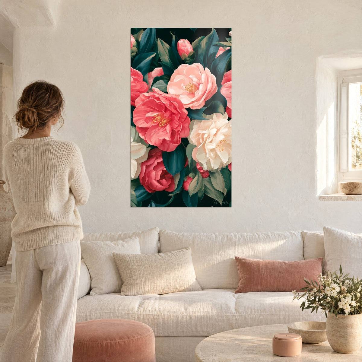 Tableau camélias corail et rose pâle sur feuillage vert sapin, femme de dos, au-dessus d'un canapé dans un salon lumineux