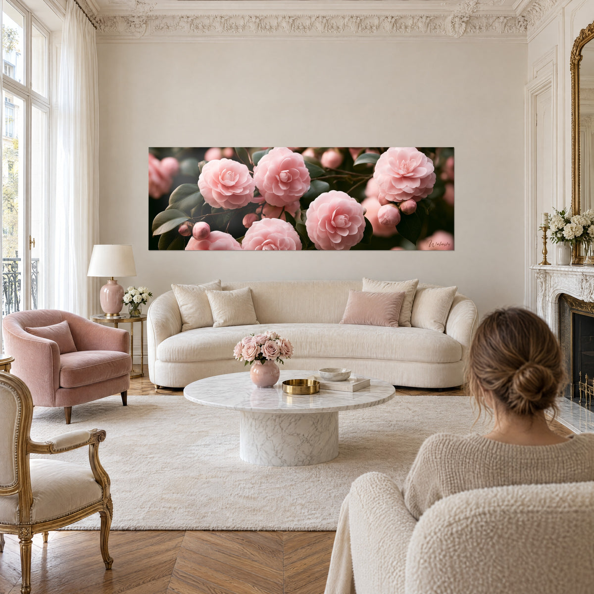Tableau camélias rose pâle en grappe serrée, feuilles vert sombre, une femme de dos, au-dessus d'un canapé dans un salon lumineux