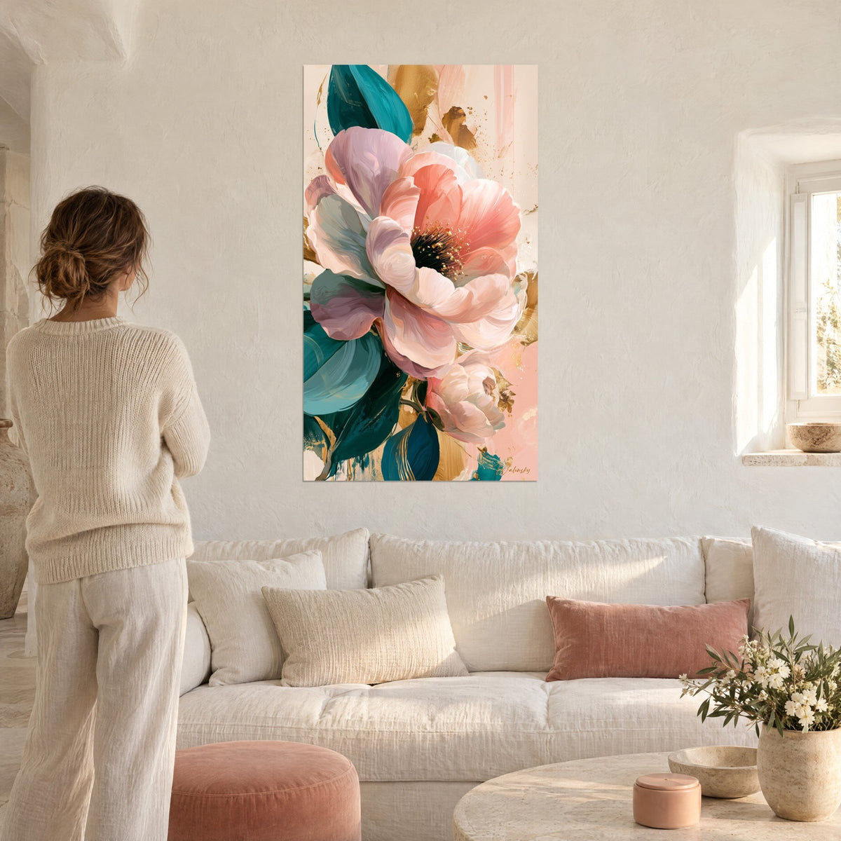 Cuadro camelia rosa salmón de pétalos empolvados, hojas turquesa y toques dorados, mujer de espaldas, sobre un sofá en un salón luminoso
