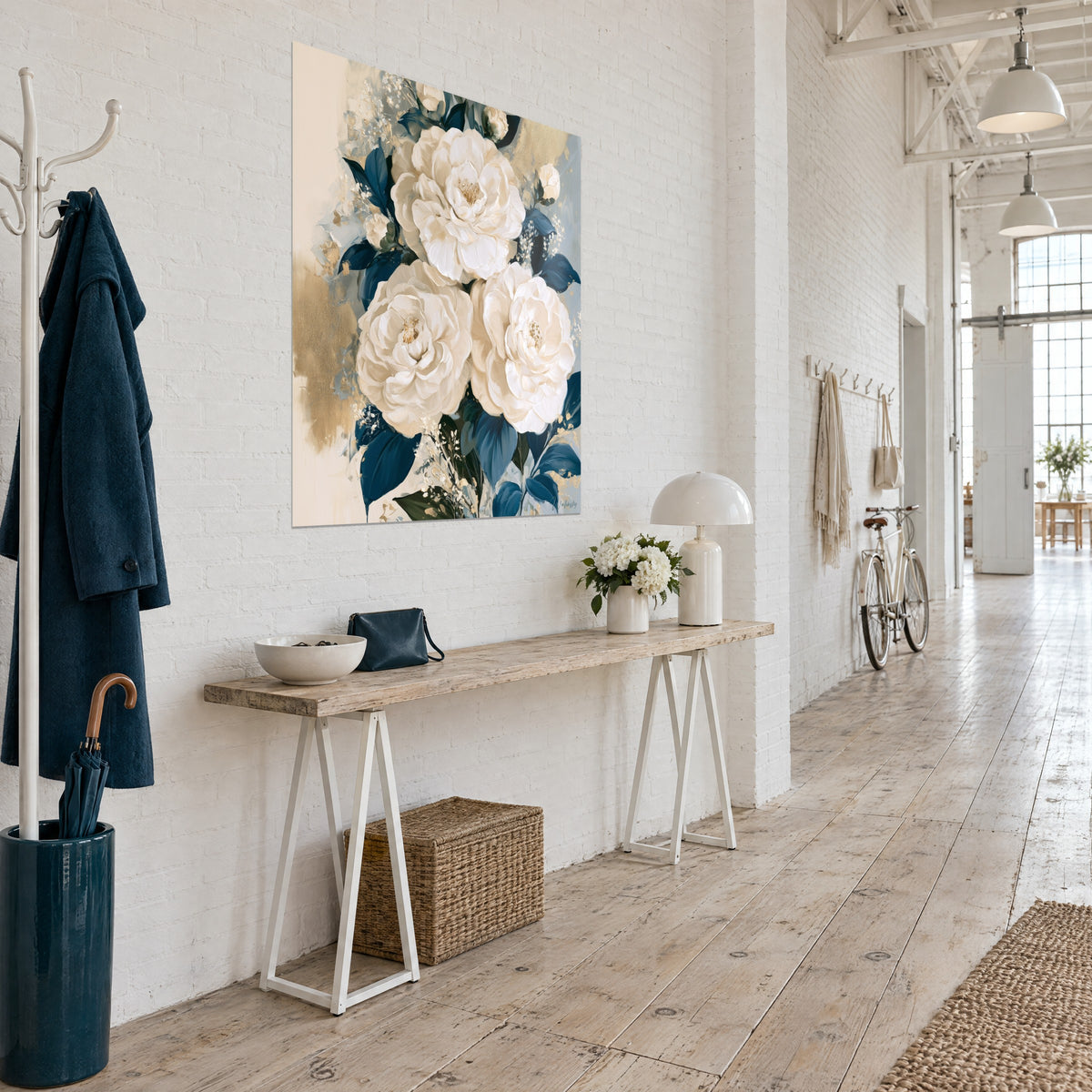 Cuadro ramo de tres grandes flores crema, follaje índigo y toques dorados, visto de tres cuartos en un loft de artista