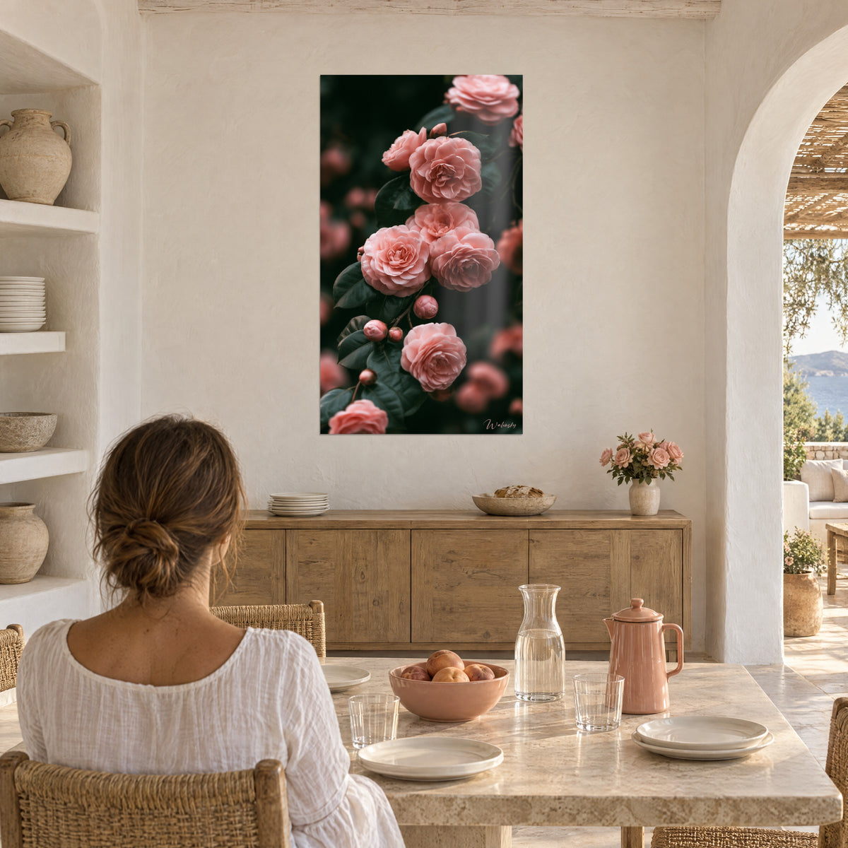 Quadro con rose antiche albicocca dai petali arricciati e foglie scure, donna di spalle seduta a un tavolo davanti a una credenza in legno chiaro