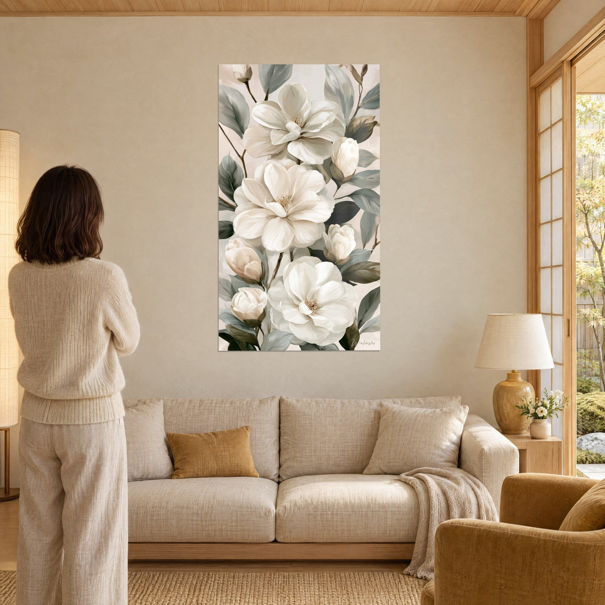 Tableau camélias ivoire aux feuilles gris-vert, cascade fleurie verticale, une femme de dos au-dessus d'un canapé dans un salon lumineux