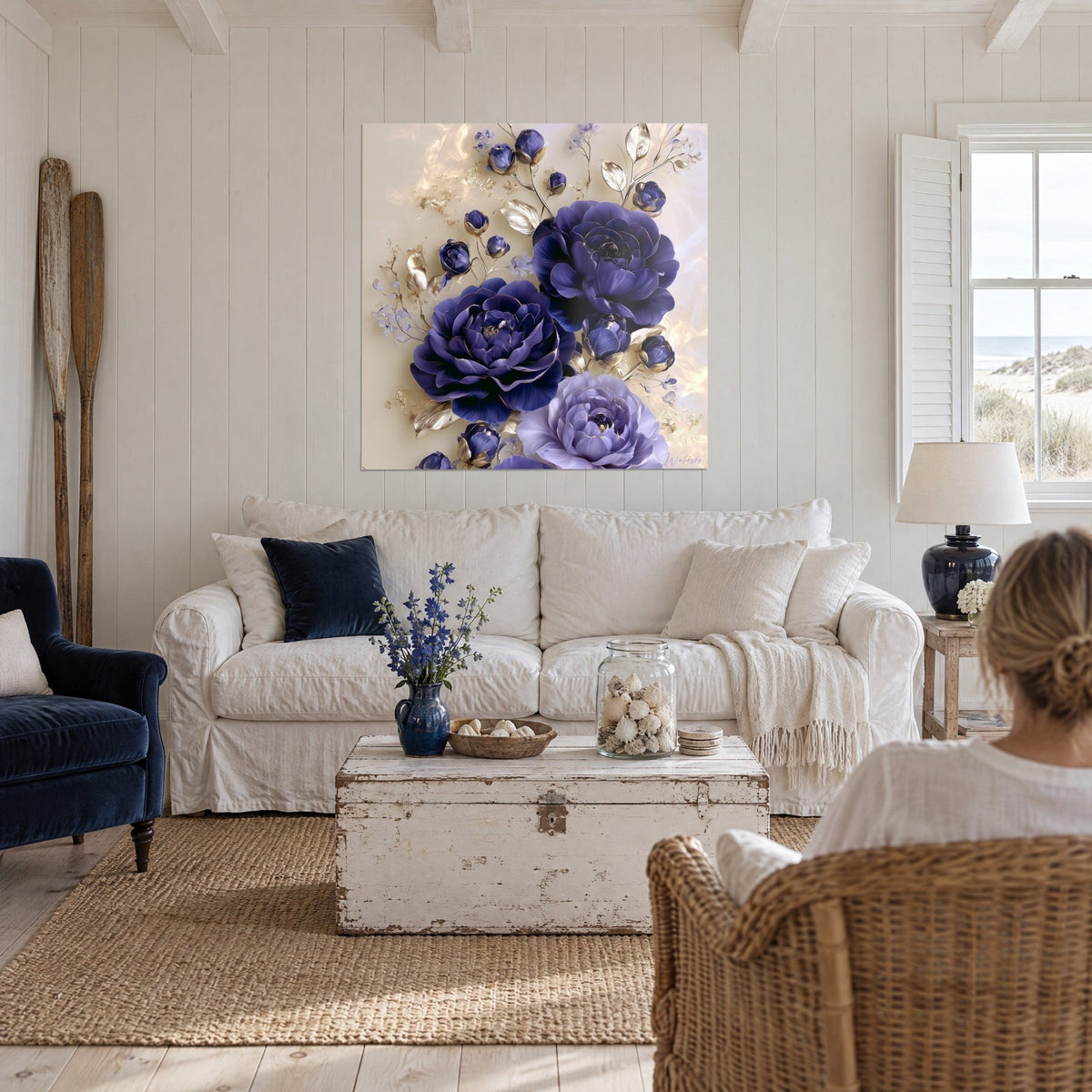 Gemälde Kamelien in Indigo mit silbrigen Blättern auf cremefarbenem Hintergrund, zwei Personen von hinten, über einem Sofa in einem hellen Wohnzimmer