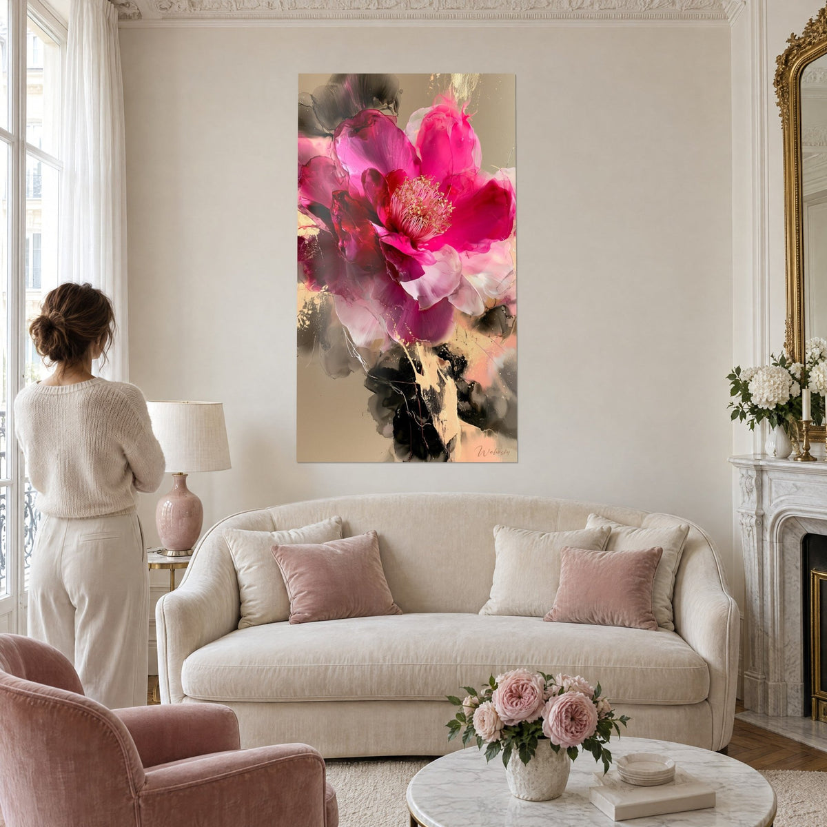 Tableau camélia fuchsia aux étamines dorées en éventail, pétales rose translucide sur fond sable, femme de dos au-dessus d'un canapé dans un salon lumineux