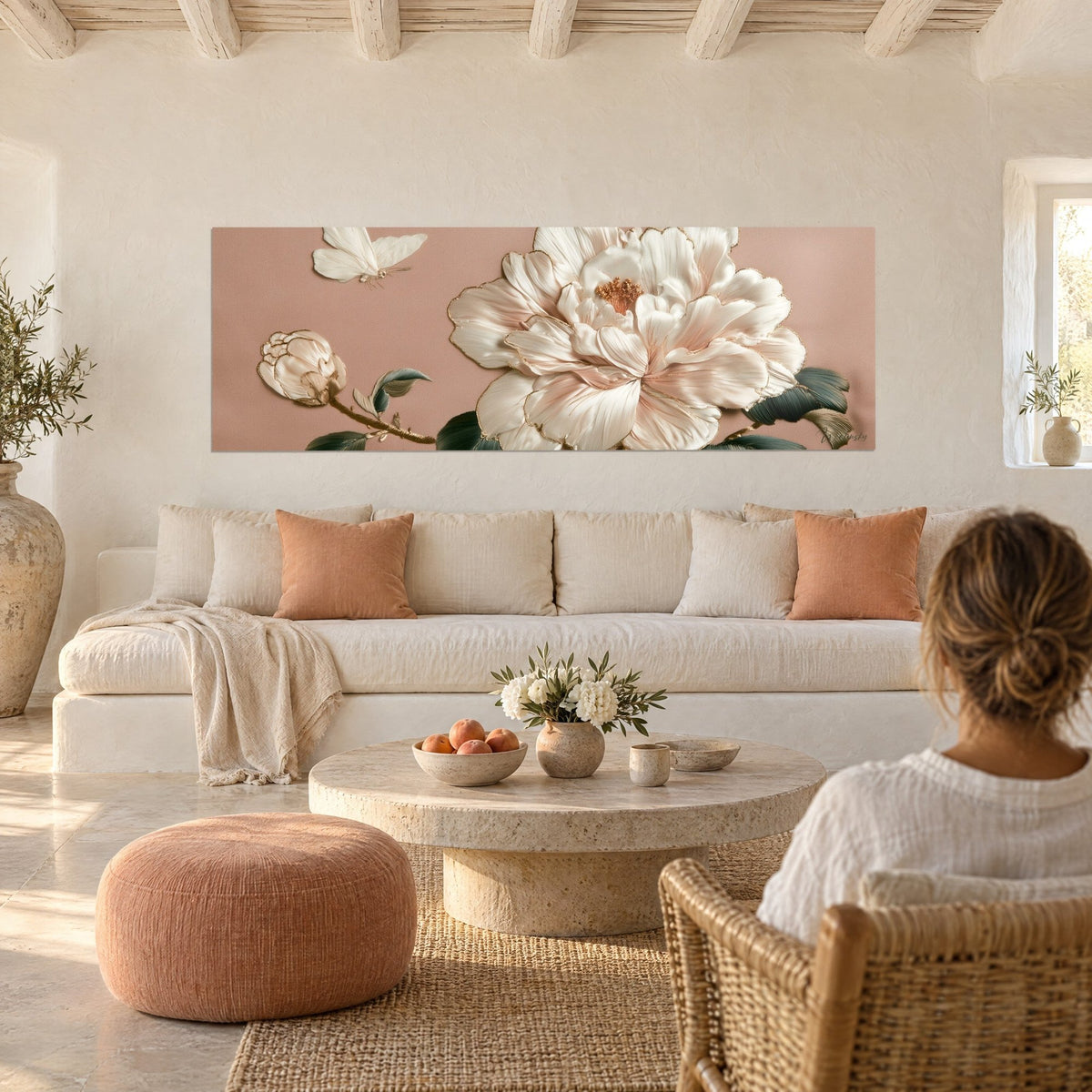 Wall art ivory camellia in relief with gold edging, white butterfly on powder pink background, above a sofa in a bright living room