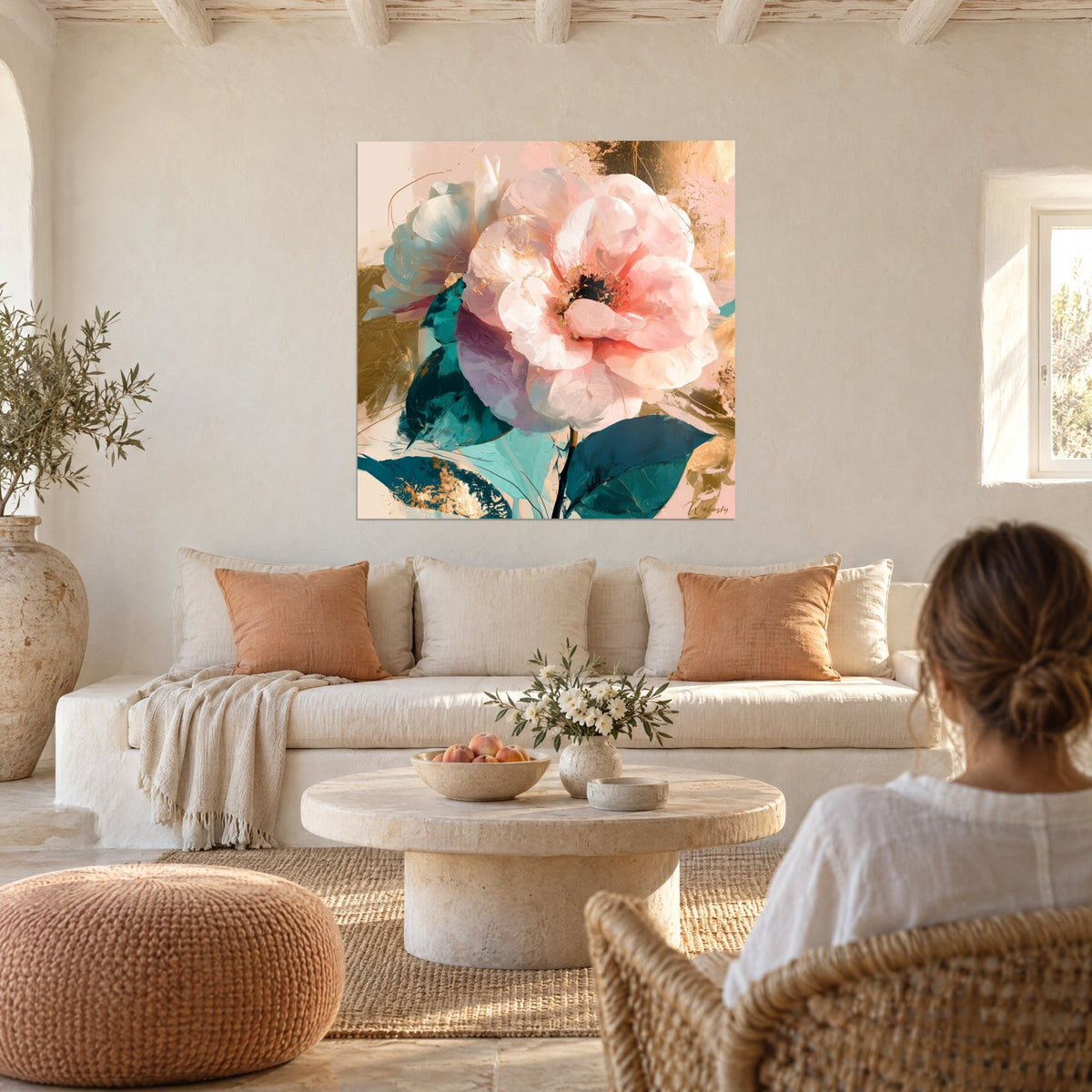 Tableau camélia rose poudré aux feuilles émeraude et touches d'or, au-dessus d'un canapé dans un salon lumineux