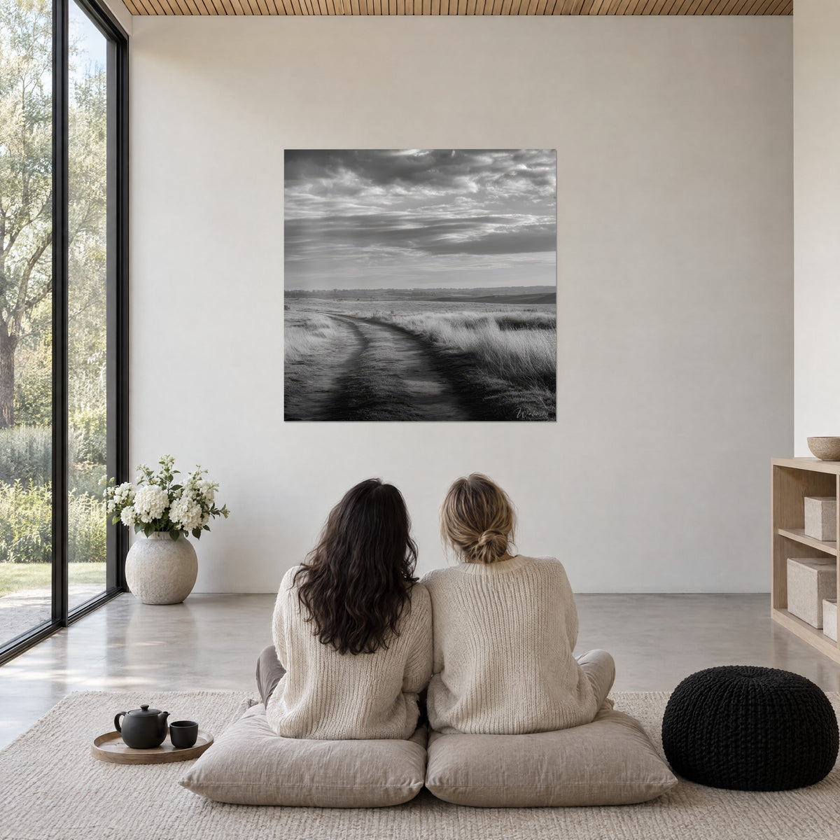 Wall art Misty moorland crossed by a dirt track, velvet black and pearl grey, cloudy sky, facing two women seated on cushions