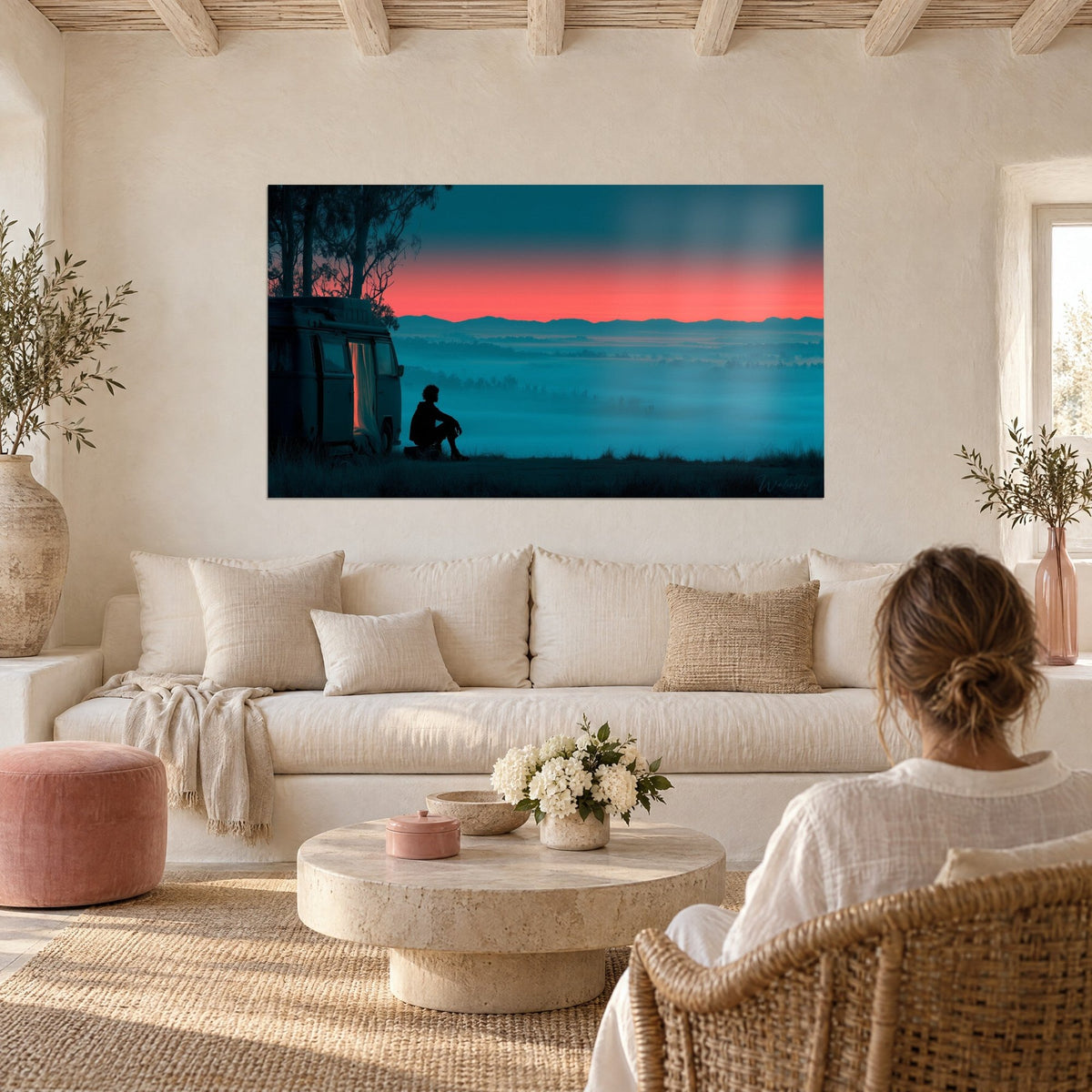 Cuadro de una escena de camping con una furgoneta en penumbra y una silueta sentada frente al amanecer rosa coral, niebla azul noche, encima de un sofá en un salón luminoso