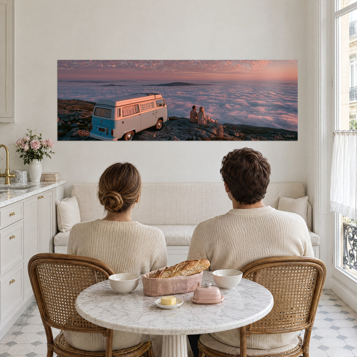 Schilderij van een van-life-tafereel op een bergtop, ivoorkleurige en oranje wolkenzee, twee zittende silhouetten, tegenover een stel dat aan tafel ontbijt