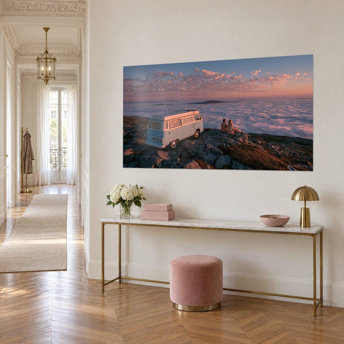 Quadro di un furgone vintage turchese appollaiato su roccia grigia, coppia seduta di fronte a nuvole arancioni, consolle dorata, ingresso in stile haussmanniano