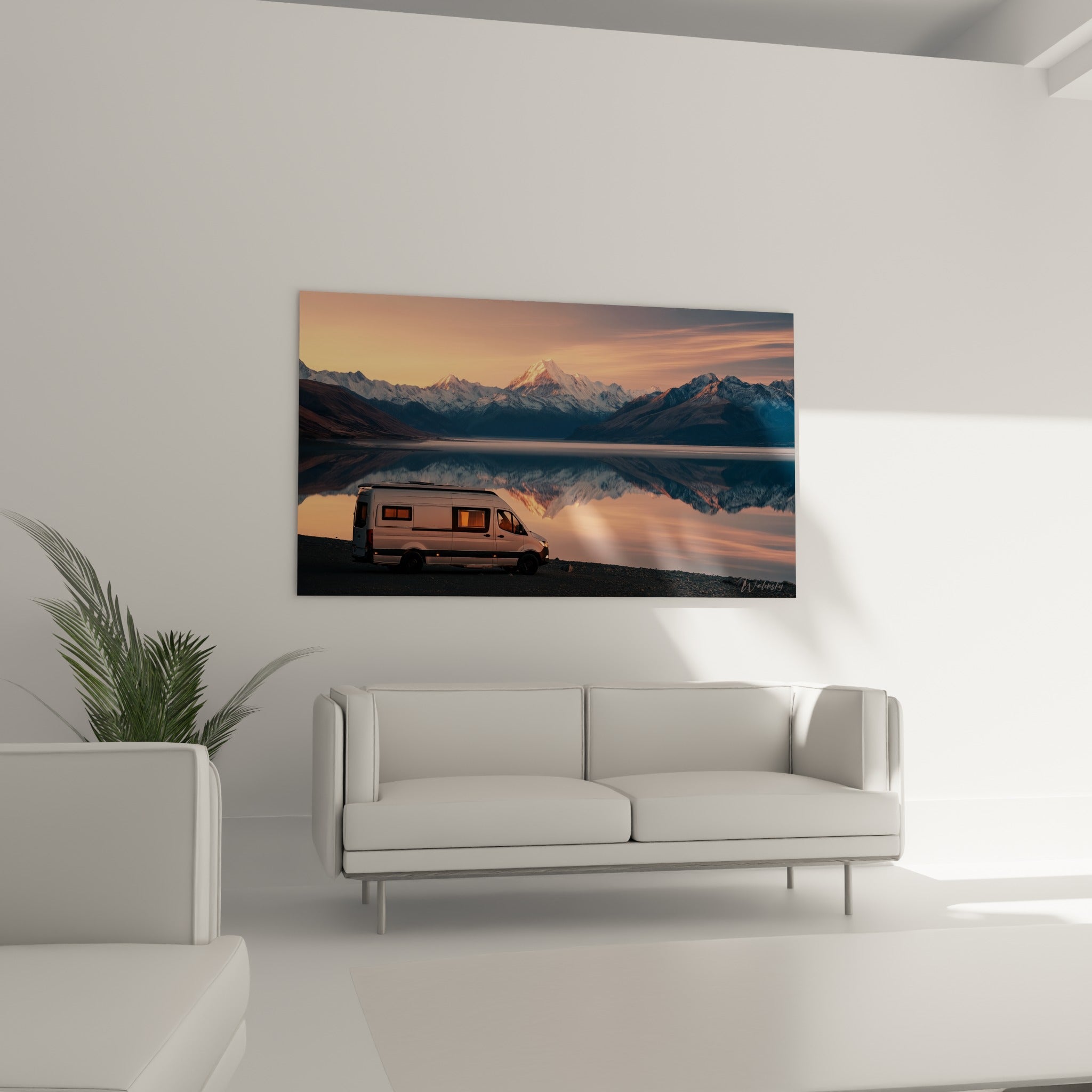 Camping-car blanc stationné devant un lac miroir ocre et bleu marine, au-dessus d'un canapé dans un salon lumineux