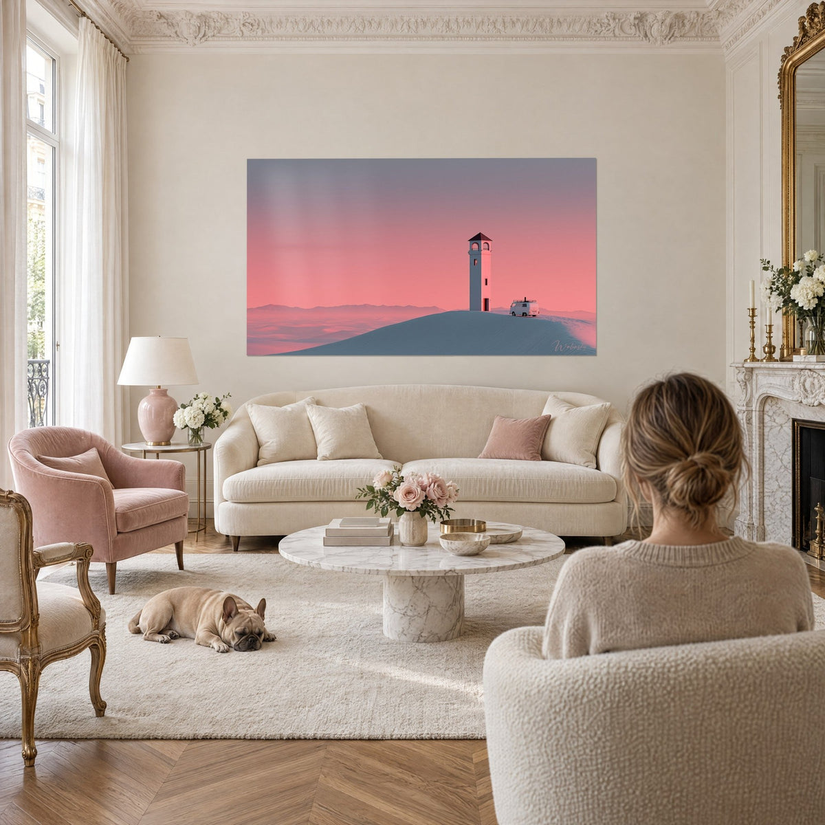 Gemälde Weißer Turm mit braunem Dach auf einer Düne, rosa und blaugrauer Himmel, davor ein parkender Van, über einem Sofa in einem hellen Wohnzimmer