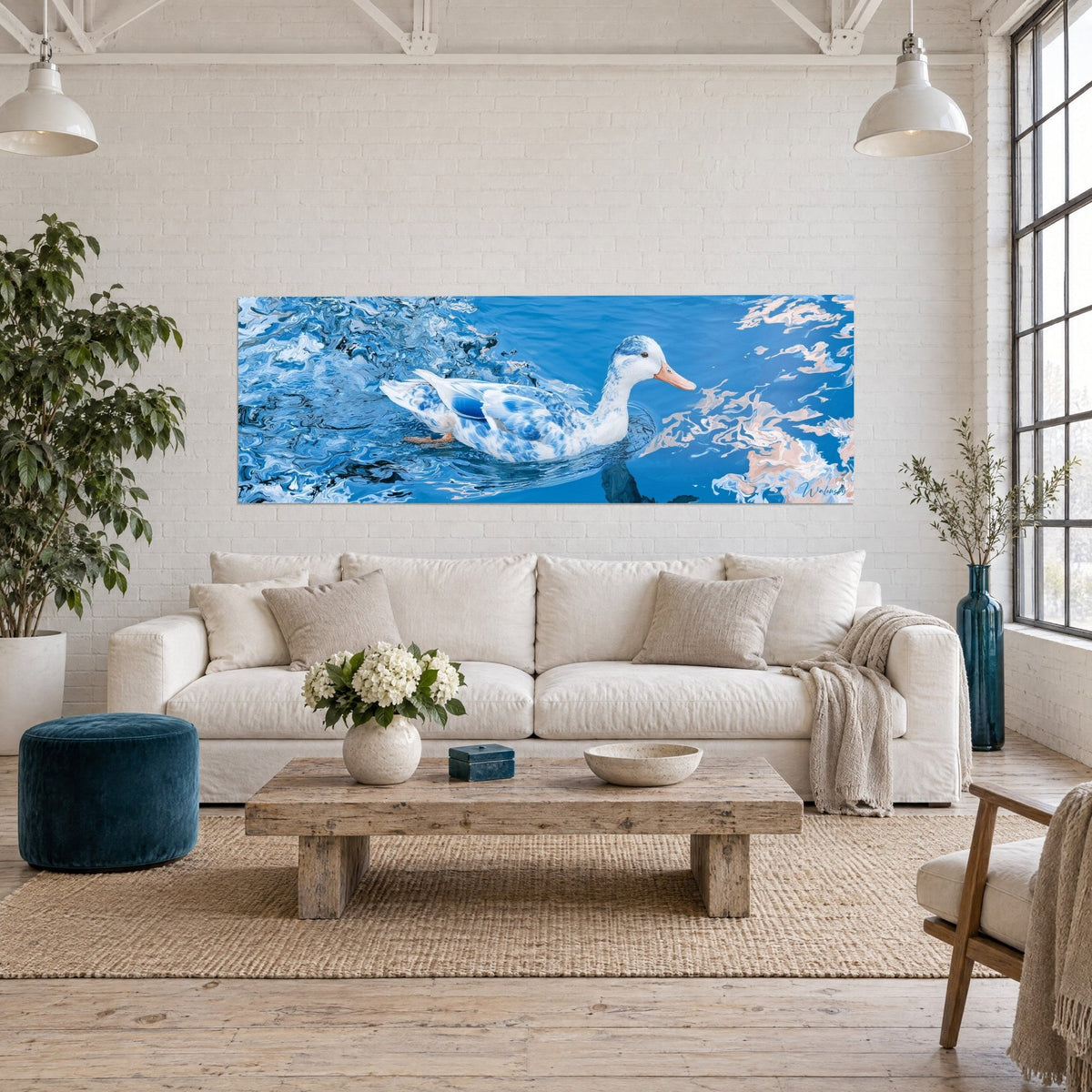 Tableau canard bleu et blanc marbré glissant sur l'eau, reflets rosés, bec orangé, au-dessus d'un canapé dans un salon lumineux