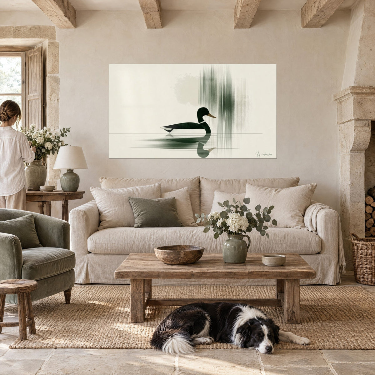 Tableau colvert stylisé vert sombre nageant sur eau beige, coulures verticales grises, collie couché sous l'œuvre, au-dessus d'un canapé dans un salon lumineux