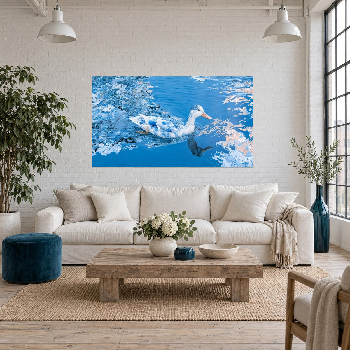 Tableau canard blanc tacheté de bleu glissant sur une eau ondulée, reflets rose pâle, au-dessus d'un canapé dans un salon lumineux