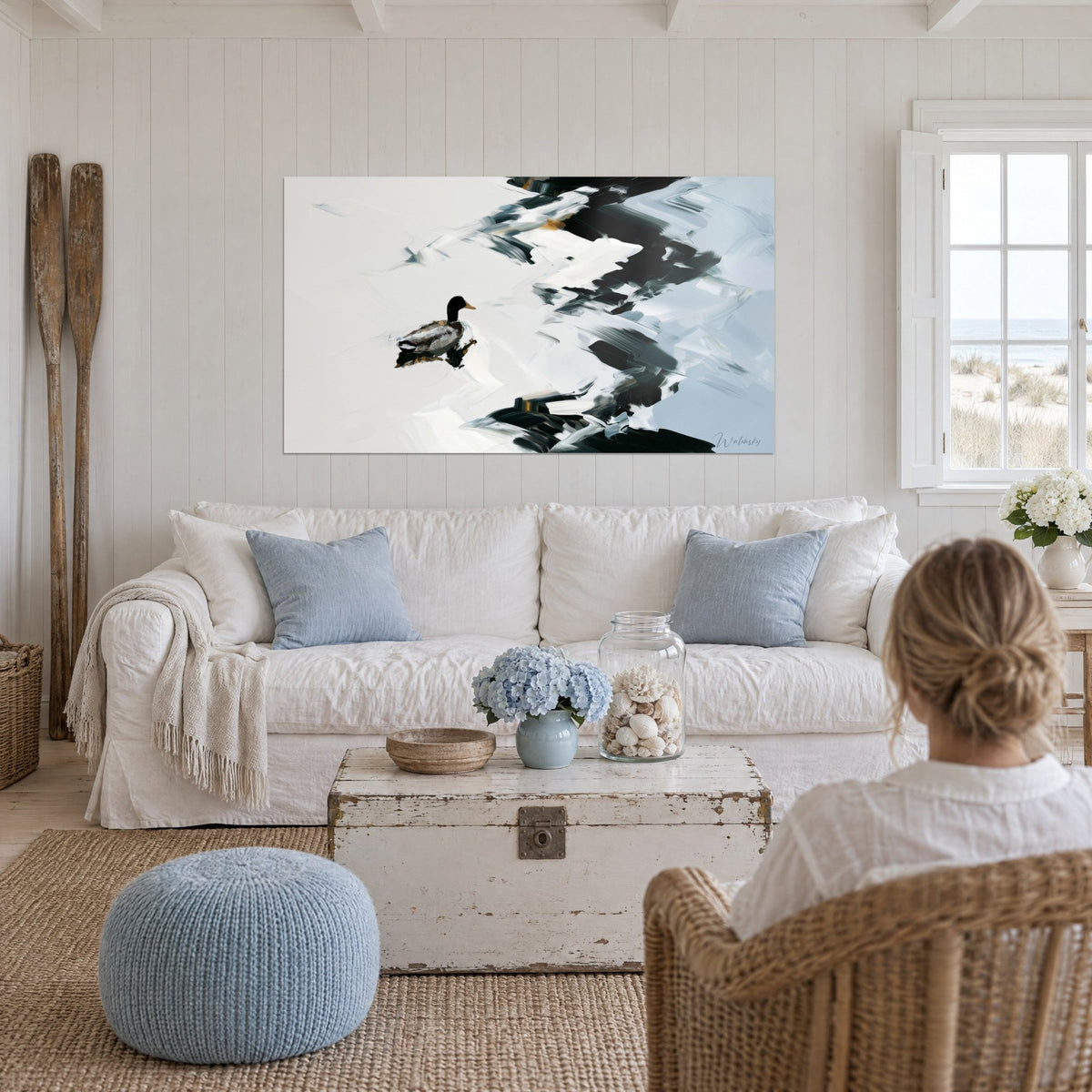 Tableau colvert glissant sur eau blanche, éclaboussures noires et bleu glacier, au-dessus d'un canapé dans un salon lumineux