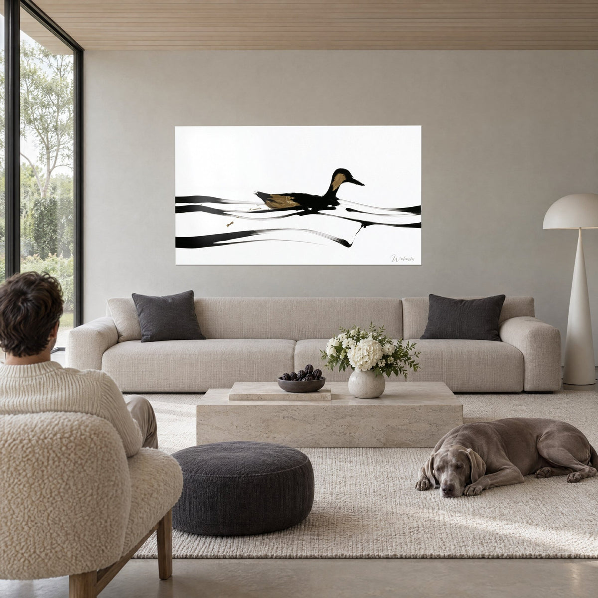 Tableau canard noir glissant sur trois vagues d'encre, plumage ocre doré sur fond blanc, au-dessus d'un canapé dans un salon lumineux