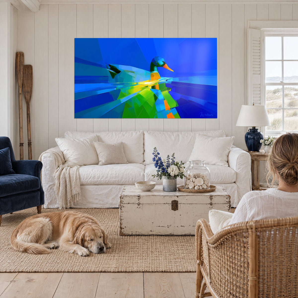 Tableau canard colvert en facettes bleu cobalt et vert prairie, bec orange, accroché au-dessus d'un canapé dans un salon lumineux