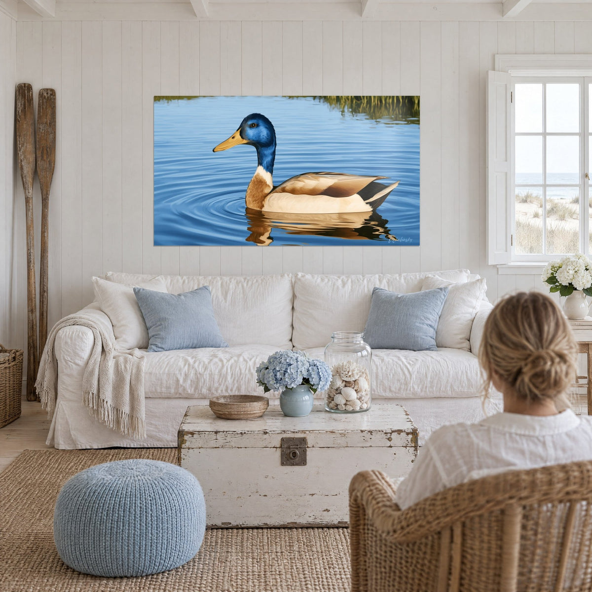 Tableau canard colvert à tête bleu cobalt glissant sur une eau azur, poitrail beige, au-dessus d'un canapé dans un salon lumineux