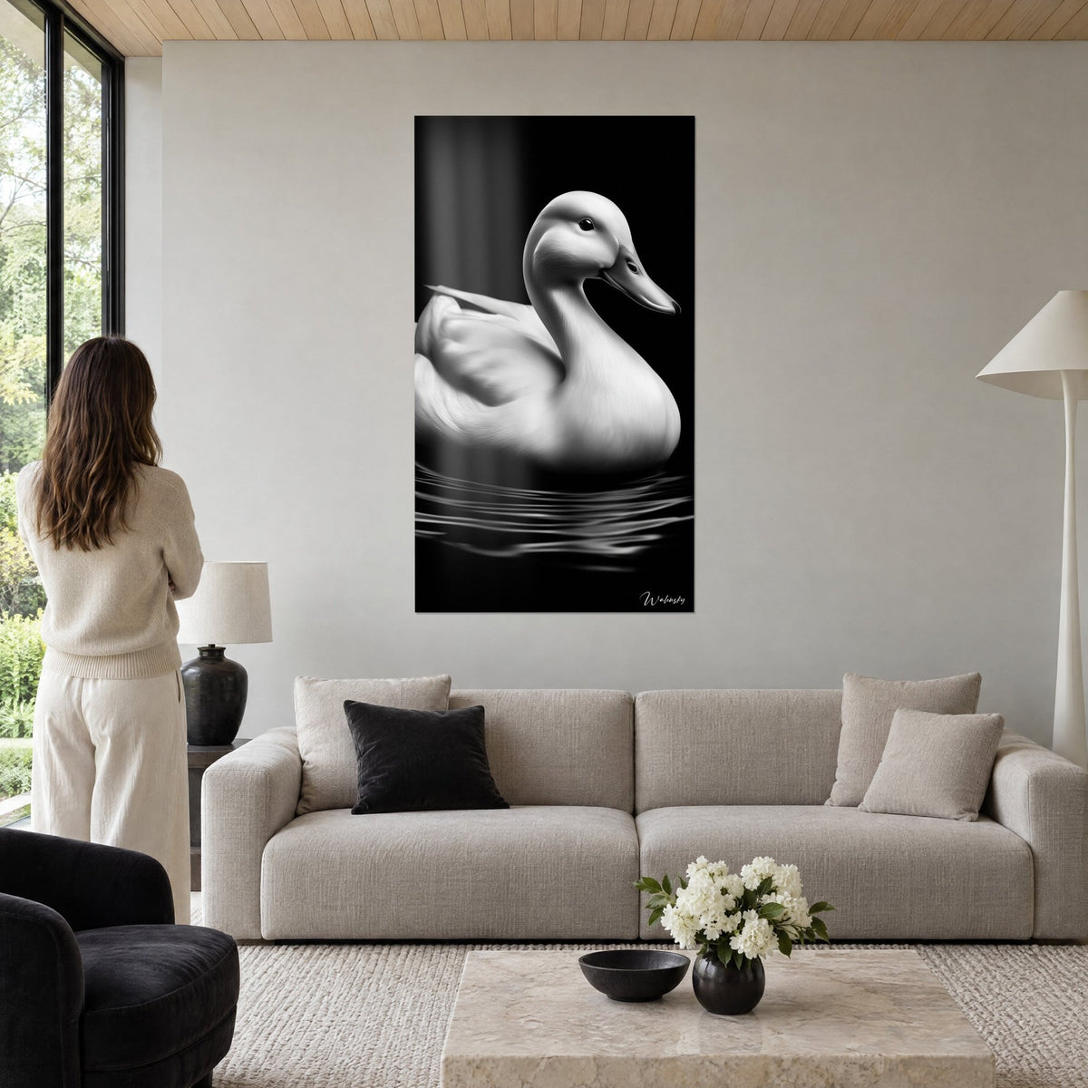 Tableau canard blanc nacré sur eau noire, cou arqué et bec fin, femme de dos, au-dessus d'un canapé dans un salon lumineux