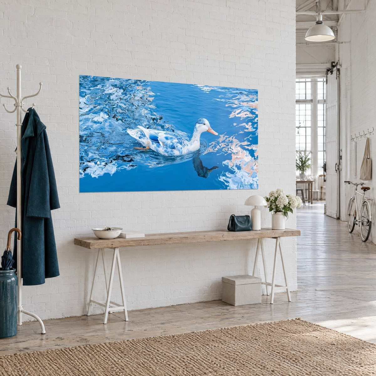 Tableau palmipède au bec orangé nageant sur un bleu profond, reflets rose saumon sur l'eau, vu de trois-quarts dans un loft