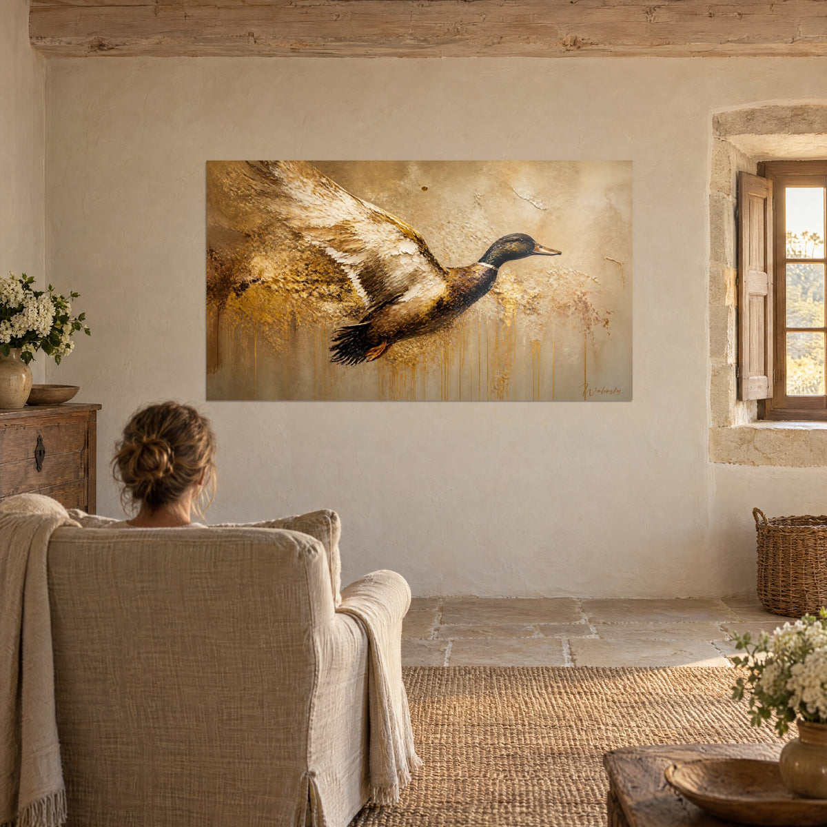Cuadro ave con las alas muy abiertas en marfil, bistre y oro, vista por una mujer de espaldas en un sillón de lino beige