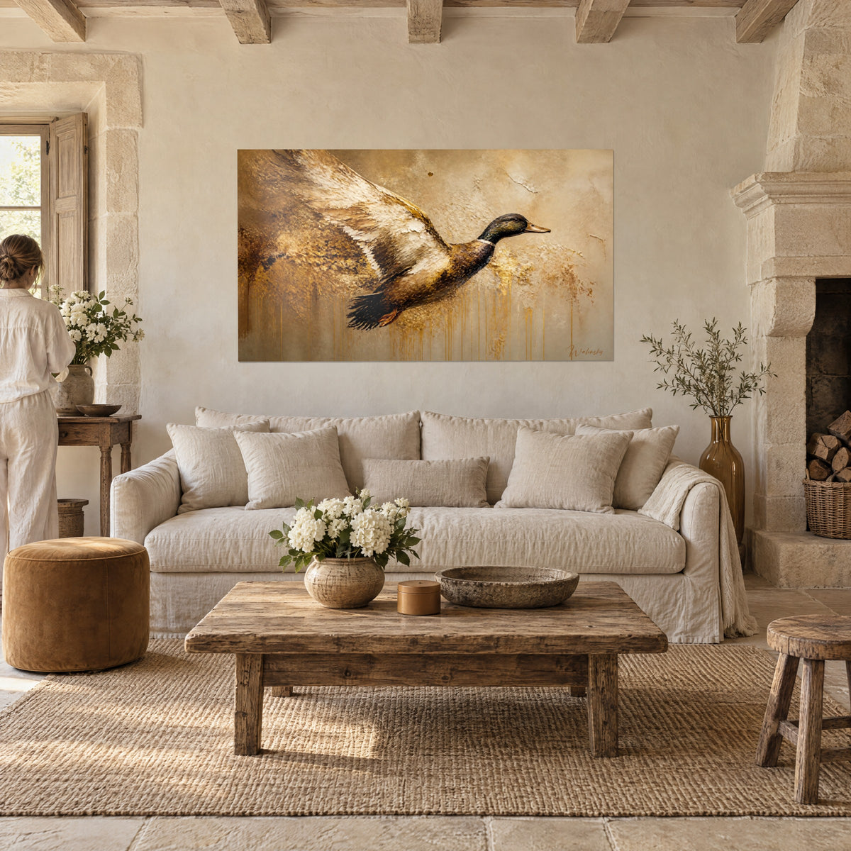 Cuadro ánade real en pleno vuelo, plumaje marrón y crema, chorreados dorados sobre fondo beige, encima de un sofá en un salón luminoso