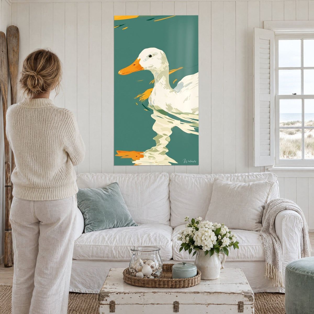 Tableau canard blanc au bec orangé glissant sur eau émeraude, reflet crème, femme de dos au-dessus d'un canapé dans un salon lumineux