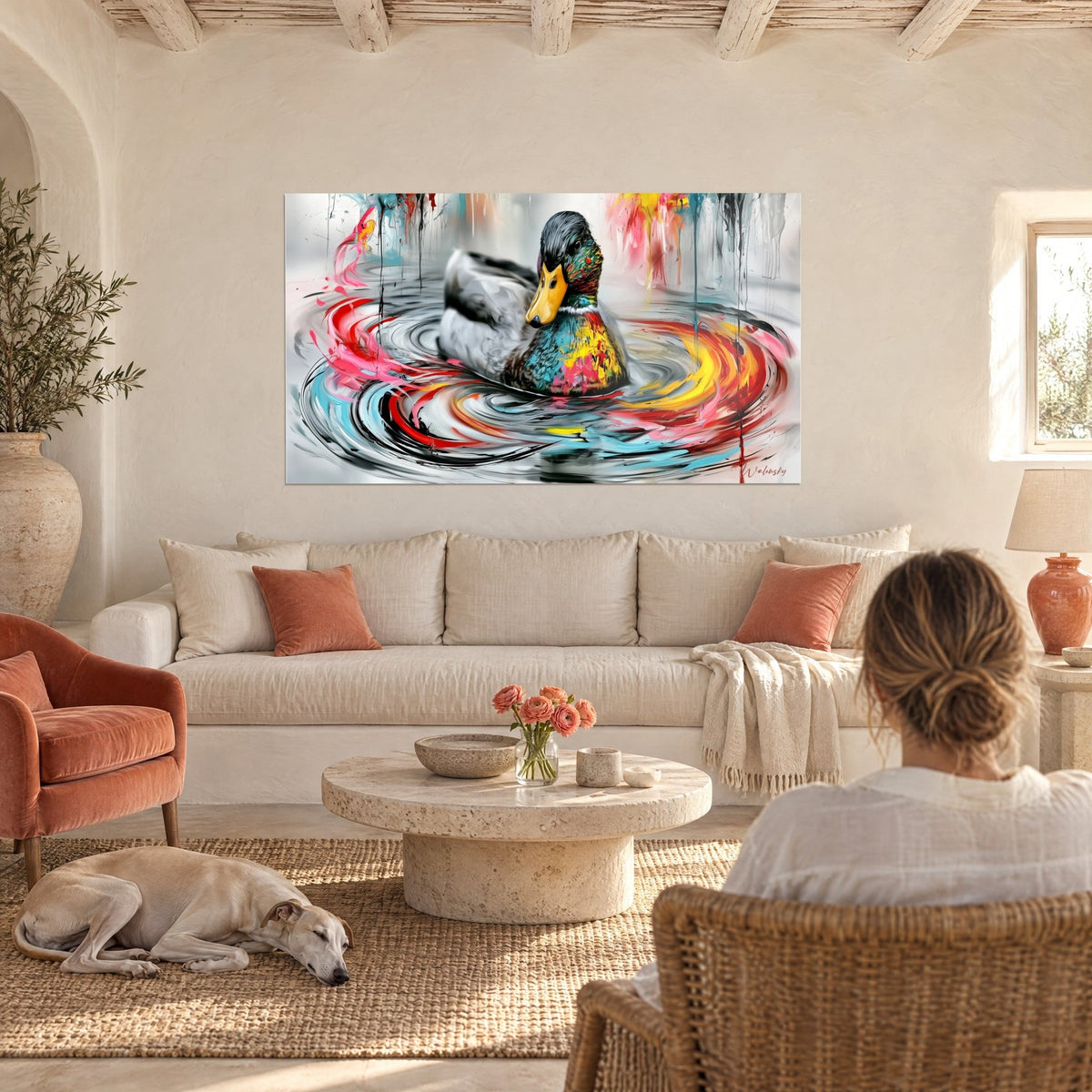 Tableau canard colvert aux plumes éclaboussées de turquoise et de jaune, une femme de dos et un lévrier, au-dessus d'un canapé dans un salon lumineux