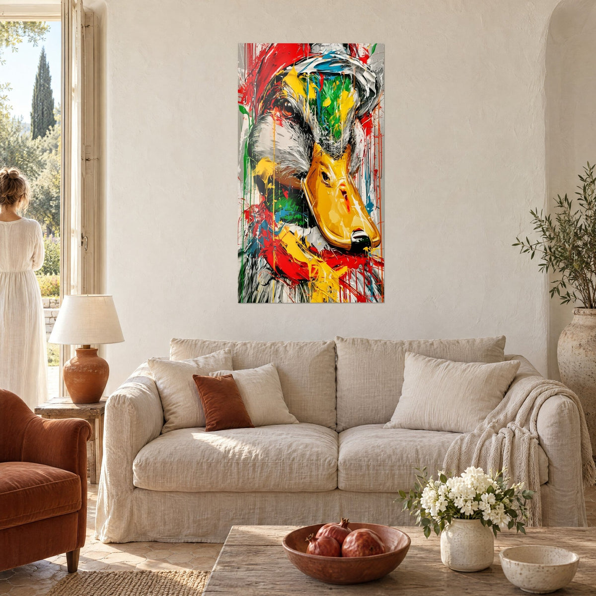 Tableau mallard au bec jaune d'or, coulures rouges et vertes, deux personnes de dos, au-dessus d'un canapé dans un salon lumineux