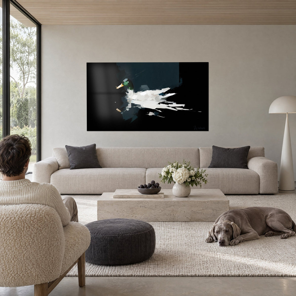 Tableau colvert flottant, tête vert émeraude et bec jaune, plumage blanc sur fond noir, au-dessus d'un canapé dans un salon lumineux