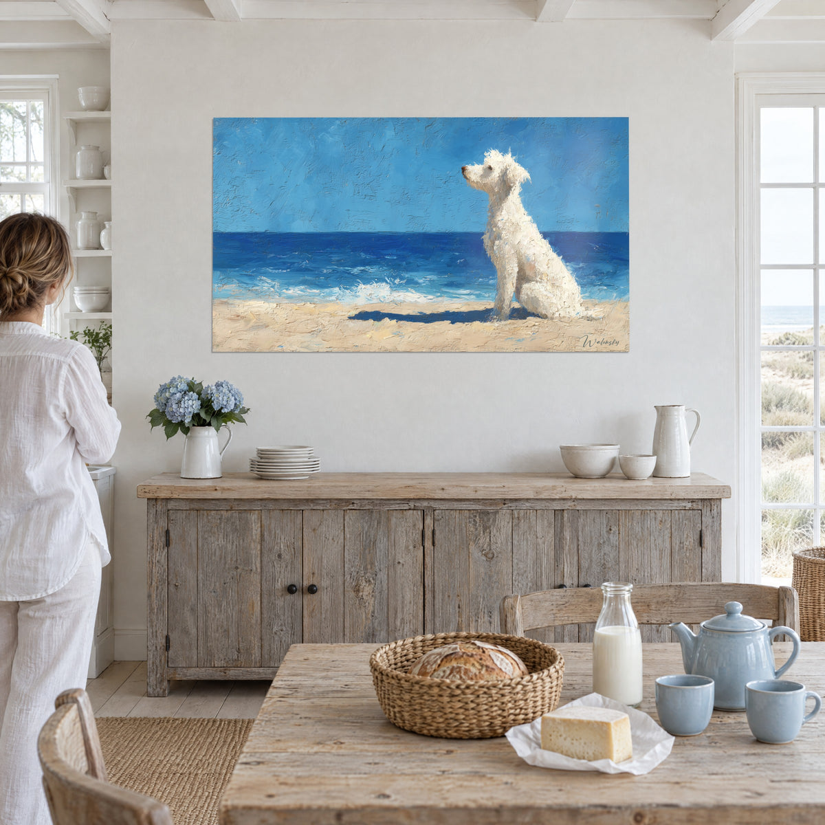 Quadro di un piccolo cane bianco di profilo sulla riva, onde di schiuma e mare zaffiro, parete bianca, donna in lino di spalle, tavolo con il pane