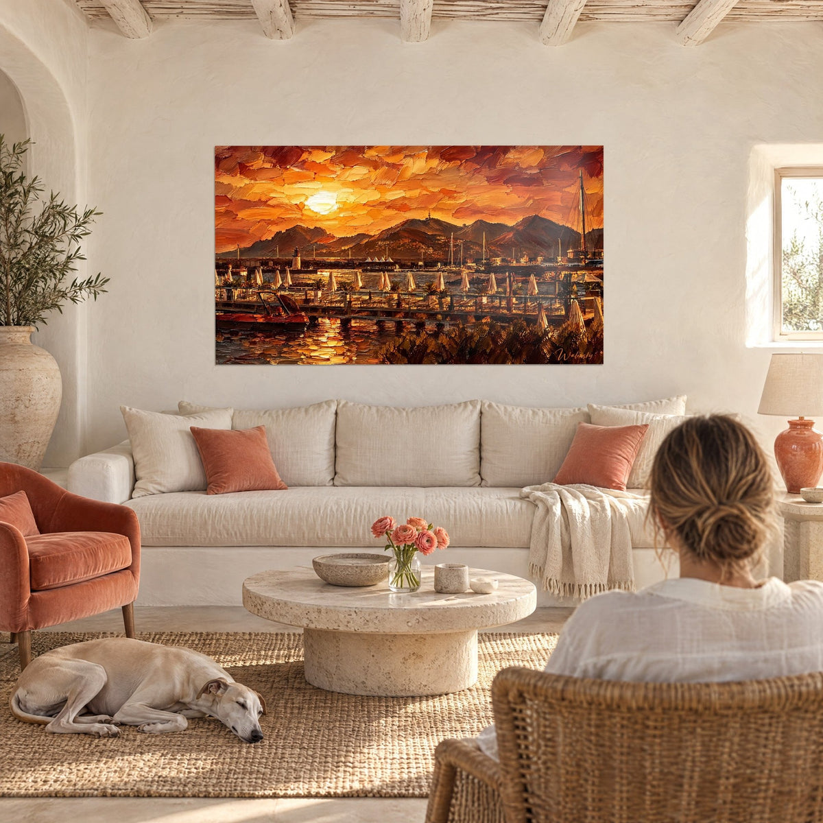 Quadro porto di Cannes al tramonto, cielo arancio e ocra, ombrelloni chiusi, molo; due persone di spalle, levriero, sopra un divano in un soggiorno luminoso